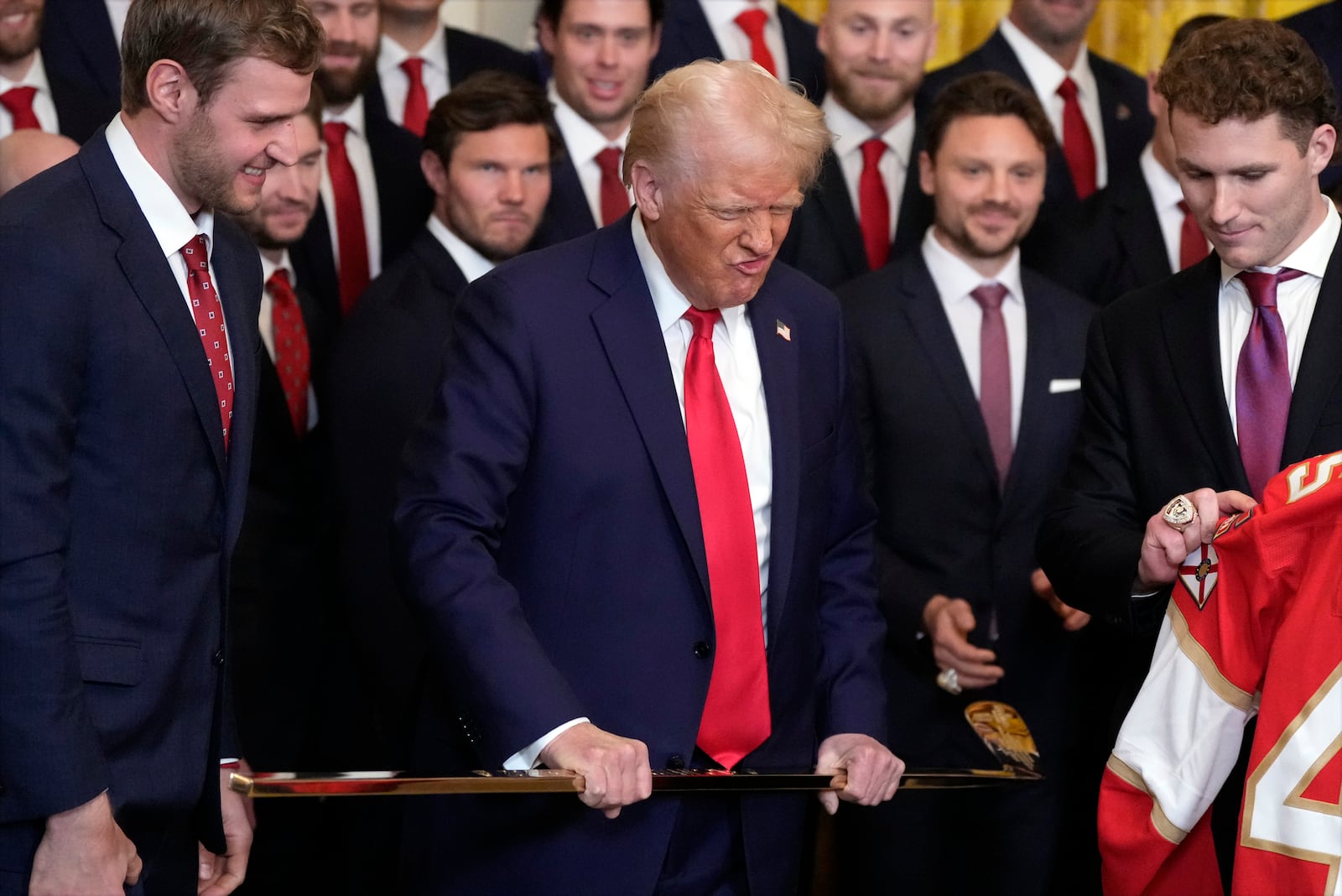 President Donald Trump holds a hockey stick before he poses for a photo with Aleksander Barkov, left, and Matthew Tkachuk during a ceremony with the Florida Panthers NHL hockey team to celebrate their 2024 Stanley Cup win, in the East Room of the White House, Monday, Feb. 3, 2025, in Washington. (AP Photo/Alex Brandon)