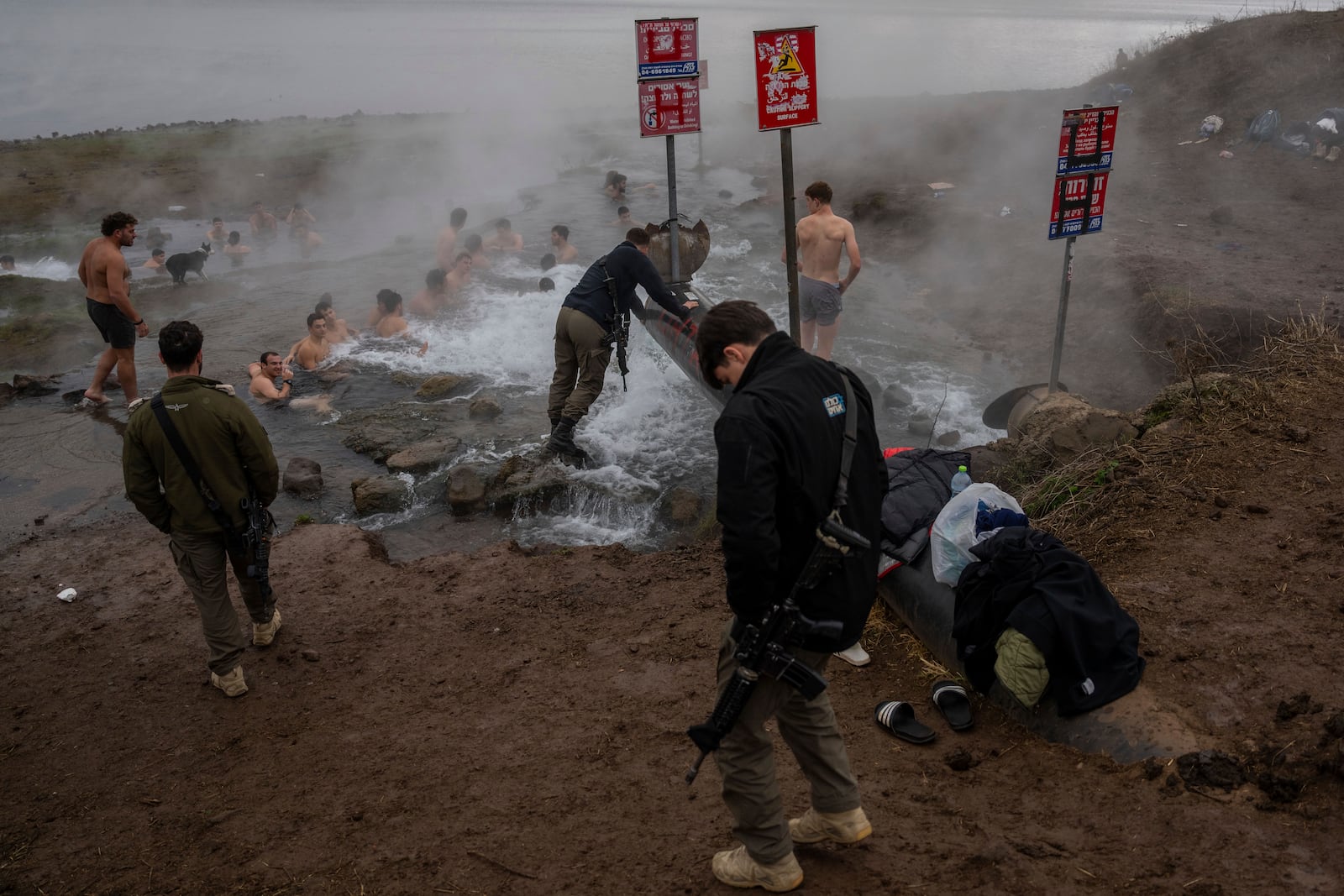 Israeli soldiers and residents bathe in a hot water coming out of a pipe from a drilling project which exposed a subterranean hydrothermal spring, at Mount Bental in the Israeli-controlled Golan Heights, on the day that the ceasefire between Israel and Hizballa began, Wednesday, Nov. 27, 2024. (AP Photo/Ohad Zwigenberg)