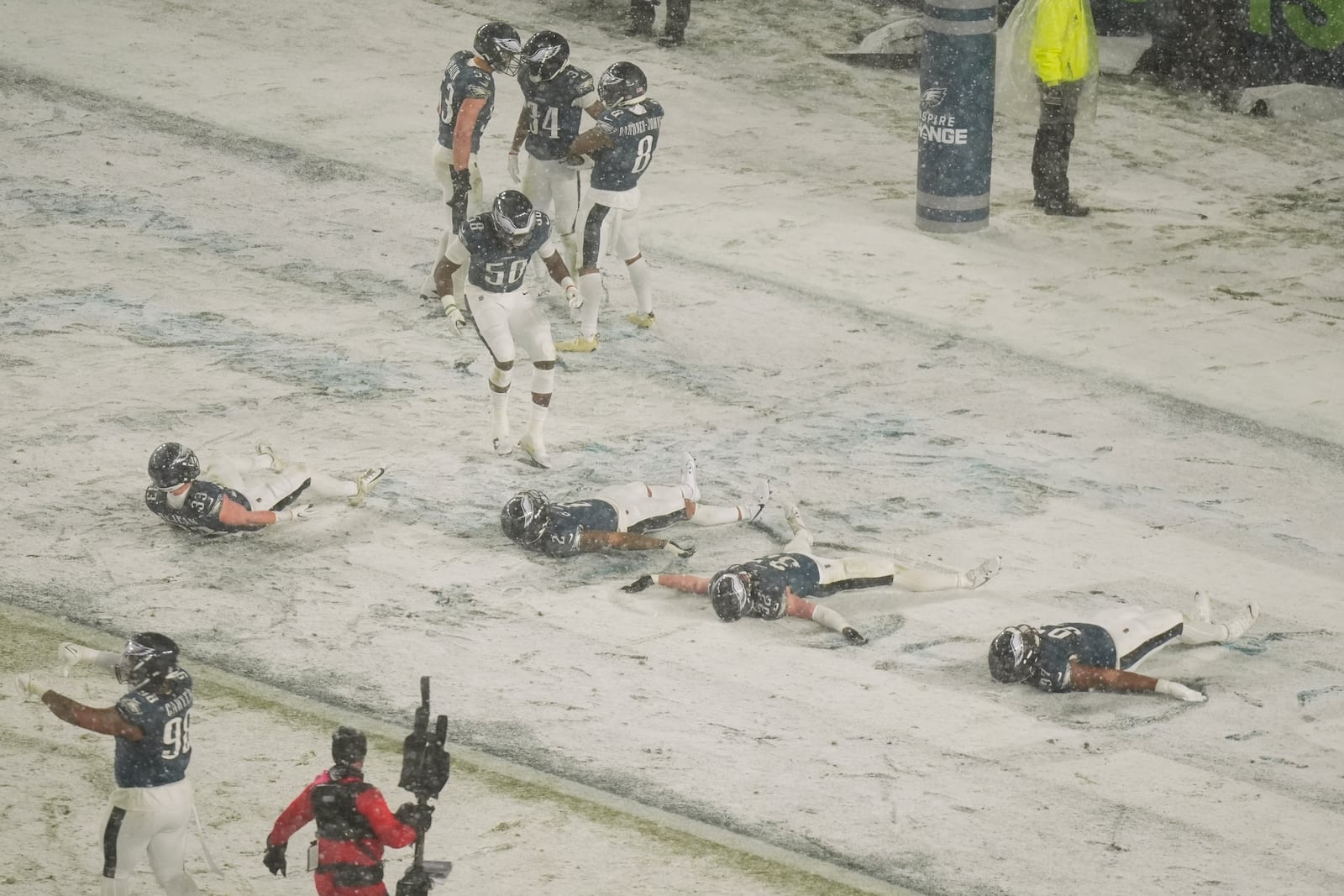 Philadelphia Eagles players do snow angels after Eagles cornerback Isaiah Rodgers (34) recovered a fumble during the second half of an NFL football NFC divisional playoff game against the Los Angeles Rams on Sunday, Jan. 19, 2025, in Philadelphia. (AP Photo/Chris Szagola)