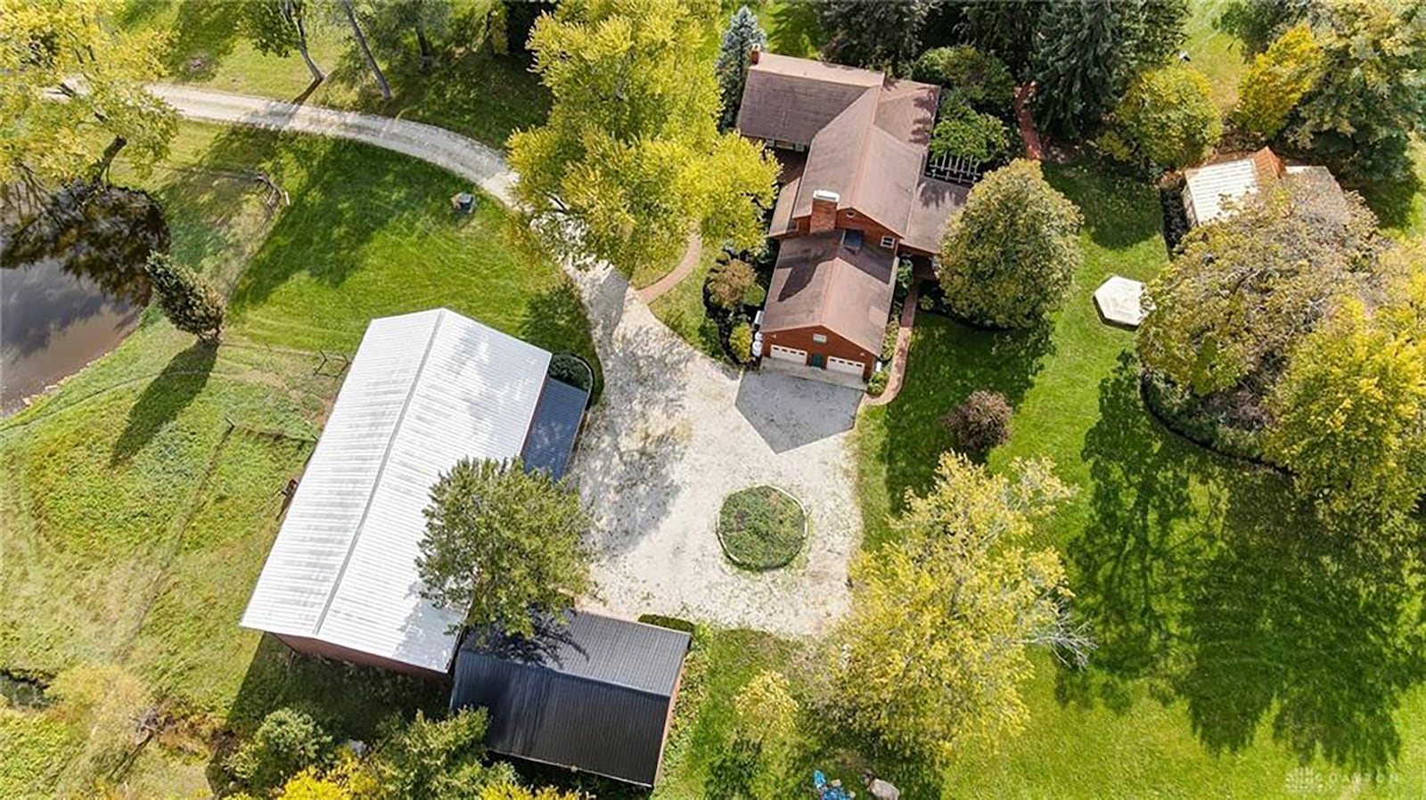 A gravel driveway leads to the home and two outbuildings, including a barn with a loft.