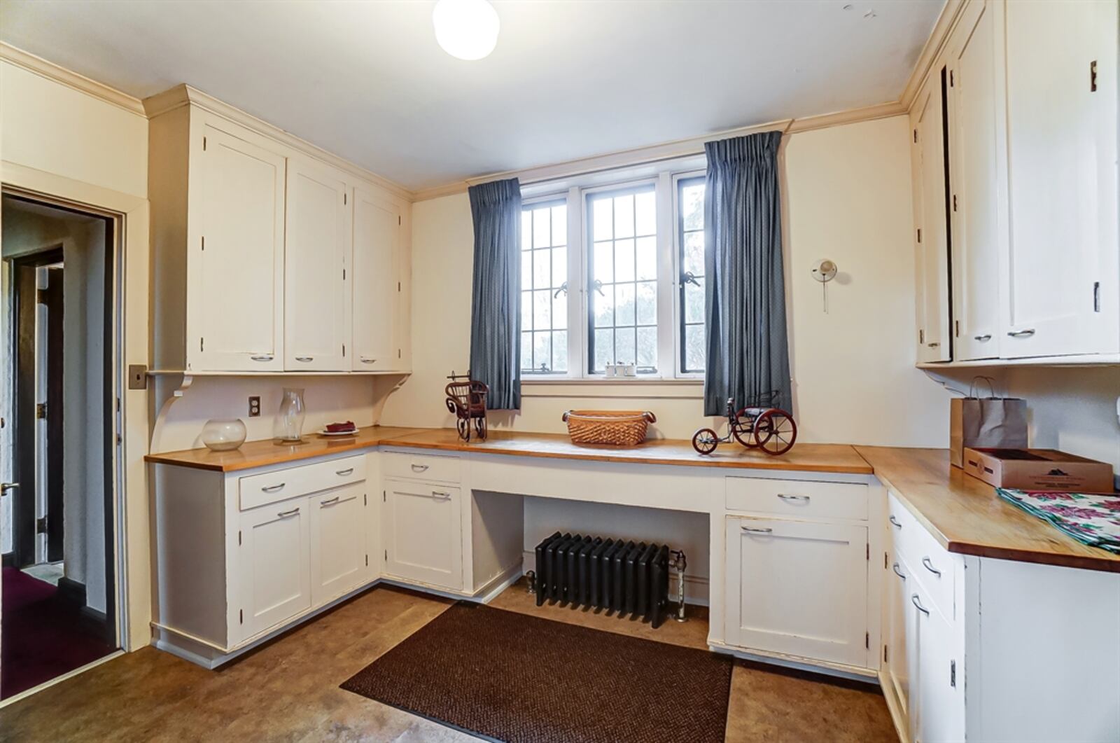 Swinging doors open into a butler’s pantry with walls of storage cabinetry and counter space and the kitchen.