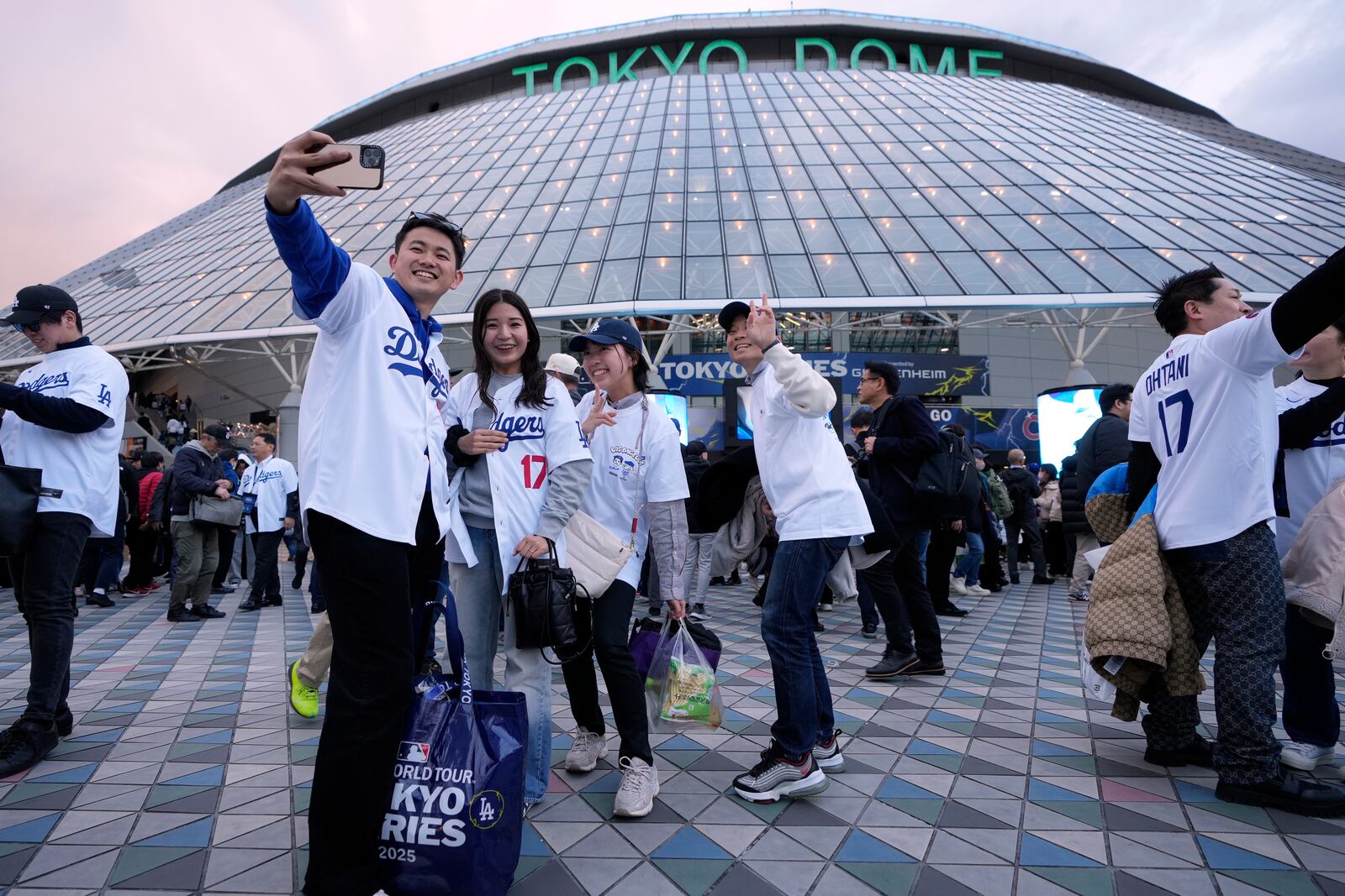 People pose for a selfie before an MLB Japan Series baseball game between the Los Angeles Dodgers and the Chicago Cubs at Tokyo Dome, in Tokyo, Tuesday, March 18, 2025. (AP Photo/Shuji Kajiyama)