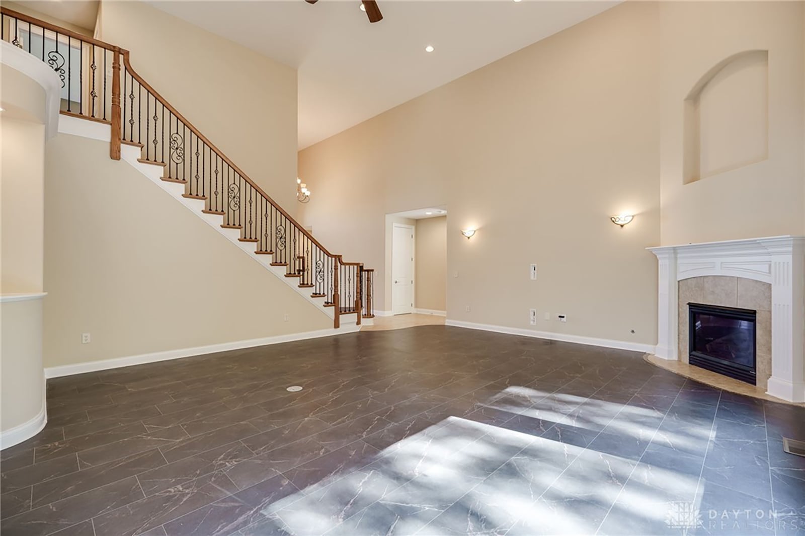 The two story family room has a corner gas fireplace and tile flooring with a wall of windows to let in natural light.