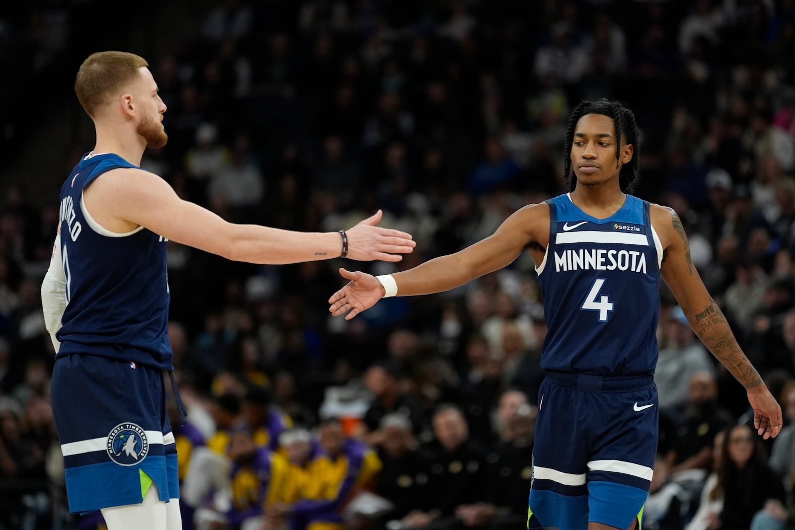 Minnesota Timberwolves guards Donte DiVincenzo (0) and Rob Dillingham (4) react during the first half of an NBA basketball game against the Los Angeles Lakers, Friday, Dec. 13, 2024, in Minneapolis. (AP Photo/Abbie Parr)