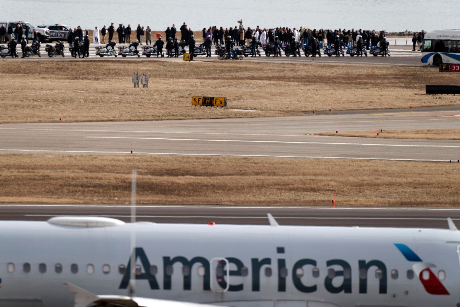 Family members of the victims of a mid-air collision between an American Airlines jet and an Army helicopter gather at the end of runway 33 near the wreckage site in the Potomac River at Ronald Reagan Washington National Airport, Sunday, Feb. 2, 2025, in Arlington, Va. (AP Photo/Jose Luis Magana)