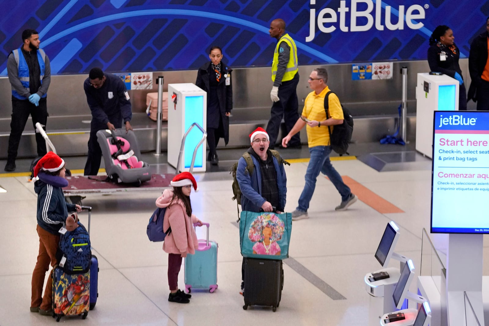 Holiday traveler Julio Henriquez of Canton, Mass., yawns while traveling with his children Marcelo and Amanda at Logan Airport, Friday, Dec. 20, 2024, in Boston. (AP Photo/Charles Krupa)