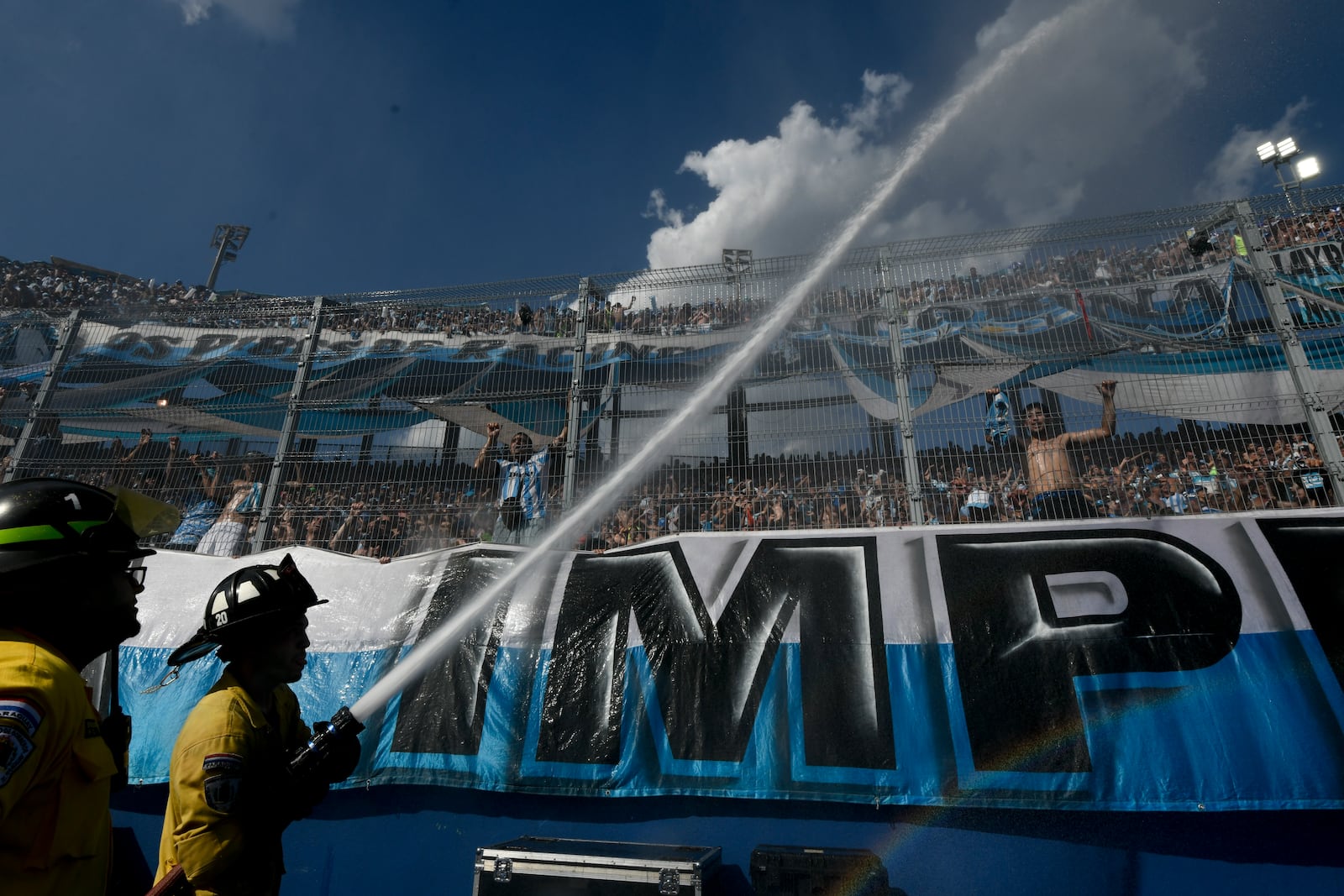 Firefighters shoot water into the crowd during the Copa Sudamericana final soccer match between Argentina's Racing Club and Brazil's Cruzeiro in Asuncion, Paraguay, Saturday, Nov. 23, 2024. (AP Photo/Gustavo Garello)