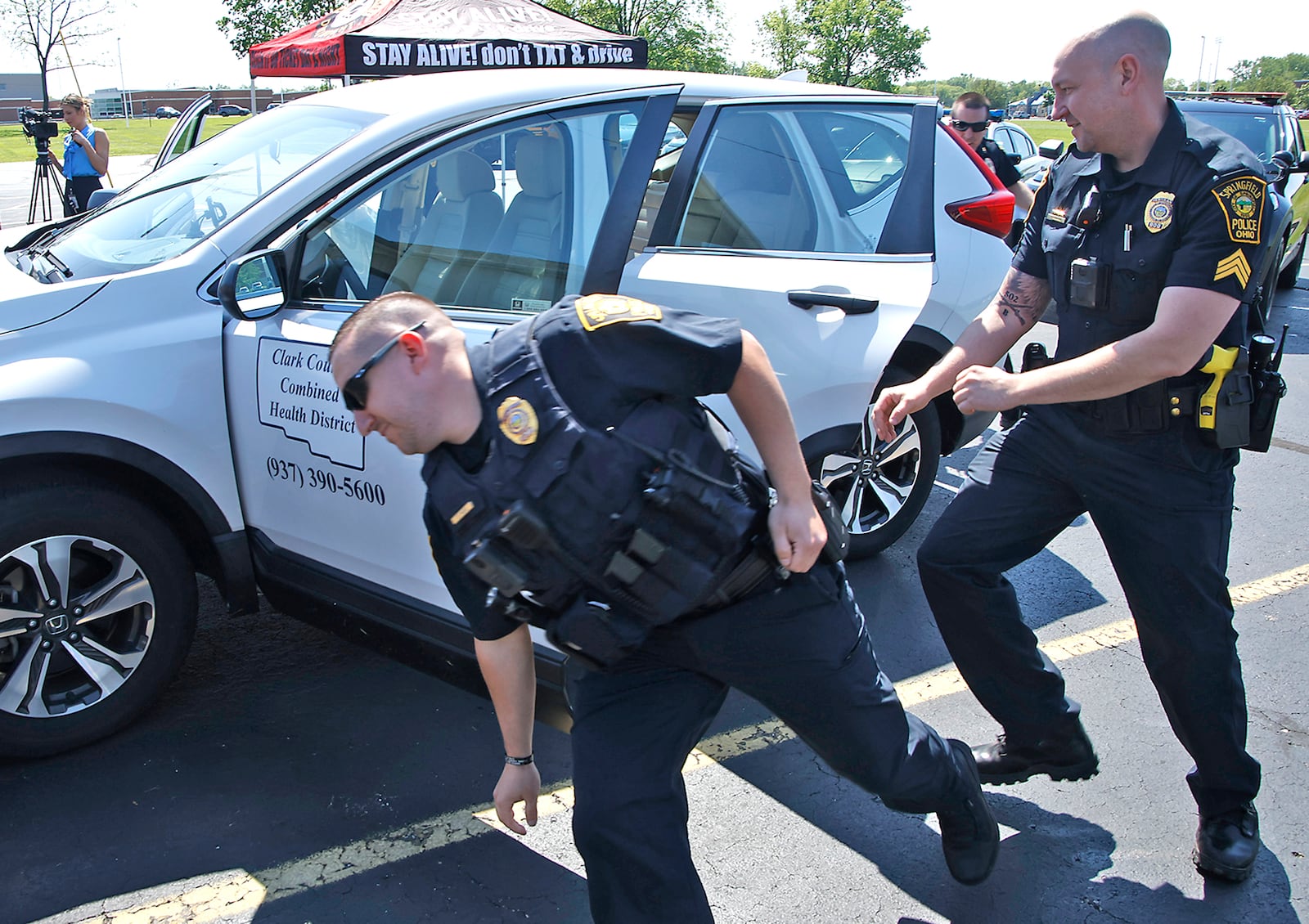 Members of area law enforcement and the Clark County Combined Health District participated in a "Quick Click Challenge" Thursday, May 16, 2024 during the Click It or Ticket campaign kick-off at the Health Department. During the challenge, four participants are timed as they quickly change positions in a car and buckle their seat belts in each seat in a car.  BILL LACKEY/STAFF