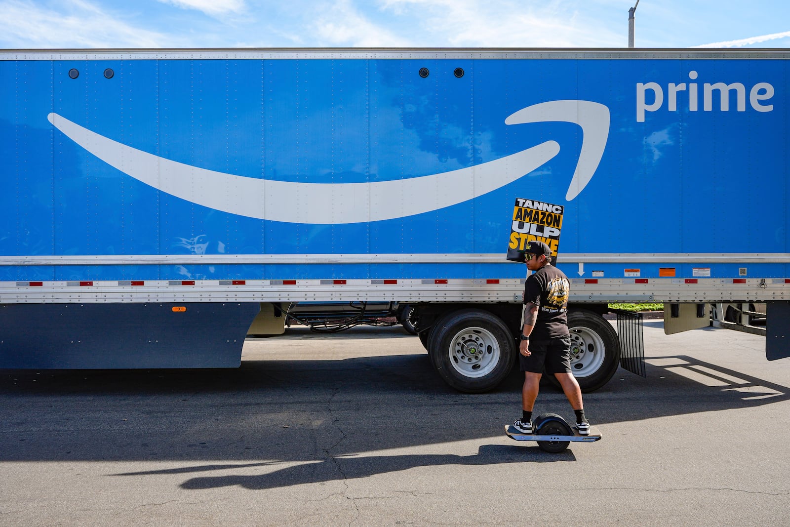 UPS driver Jhon Solidum, a member of the Teamsters union, rides a one wheeler to support the Amazon workers striking outside an Amazon Fulfillment Center as Teamsters seek labor contract nationwide, Thursday, Dec. 19, 2024, in City of Industry, Calif. (AP Photo/Damian Dovarganes)