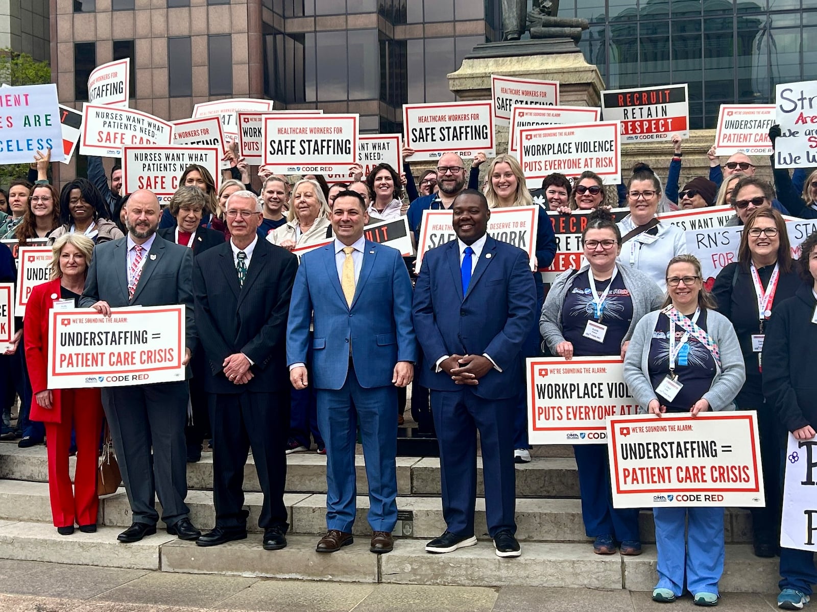 Ron Smith (front row, black suit), the father of the late Tristin Kate Smith, a Dayton nurse who died by suicide last year, poses beside Rep. Haraz Ghanbari (blue suit, yellow tie) and Rep. Elgin Rogers (blue suit, blue tie) on Wednesday, April 24, 2024. The bipartisan state reps are behind a bill to establish mandatory nurse-to-patient ratios in Ohio hospitals. AVERY KREEMER/STAFF