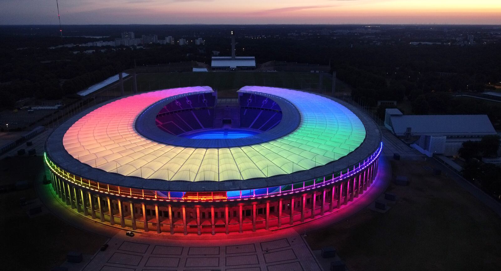 FILE - The sun sets behind the rainbow-illuminated Olympic Stadium in Berlin, Germany, Wednesday, June 23, 2021. (AP Photo/Michael Sohn, File)