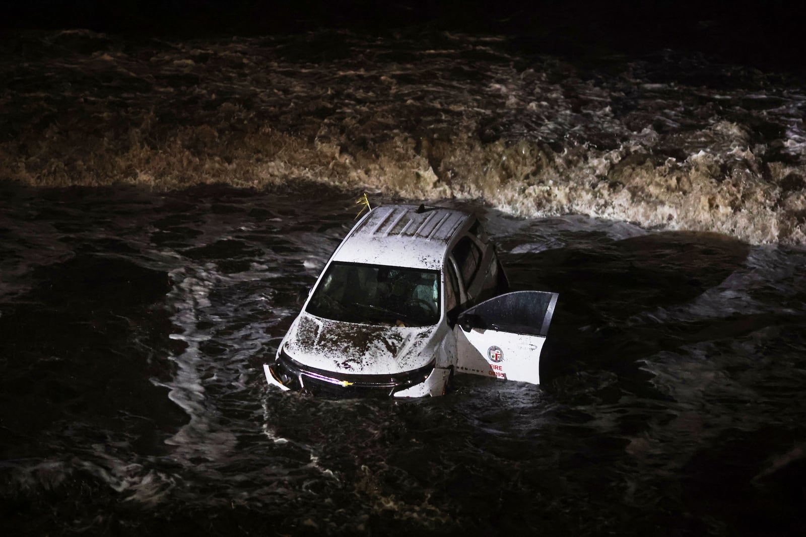 An emergency vehicle is hit by surf after being pushed into the ocean during a storm in the Palisades Fire zone Thursday, Feb. 13, 2025, in Malibu, Calif. (AP Photo/Ethan Swope)