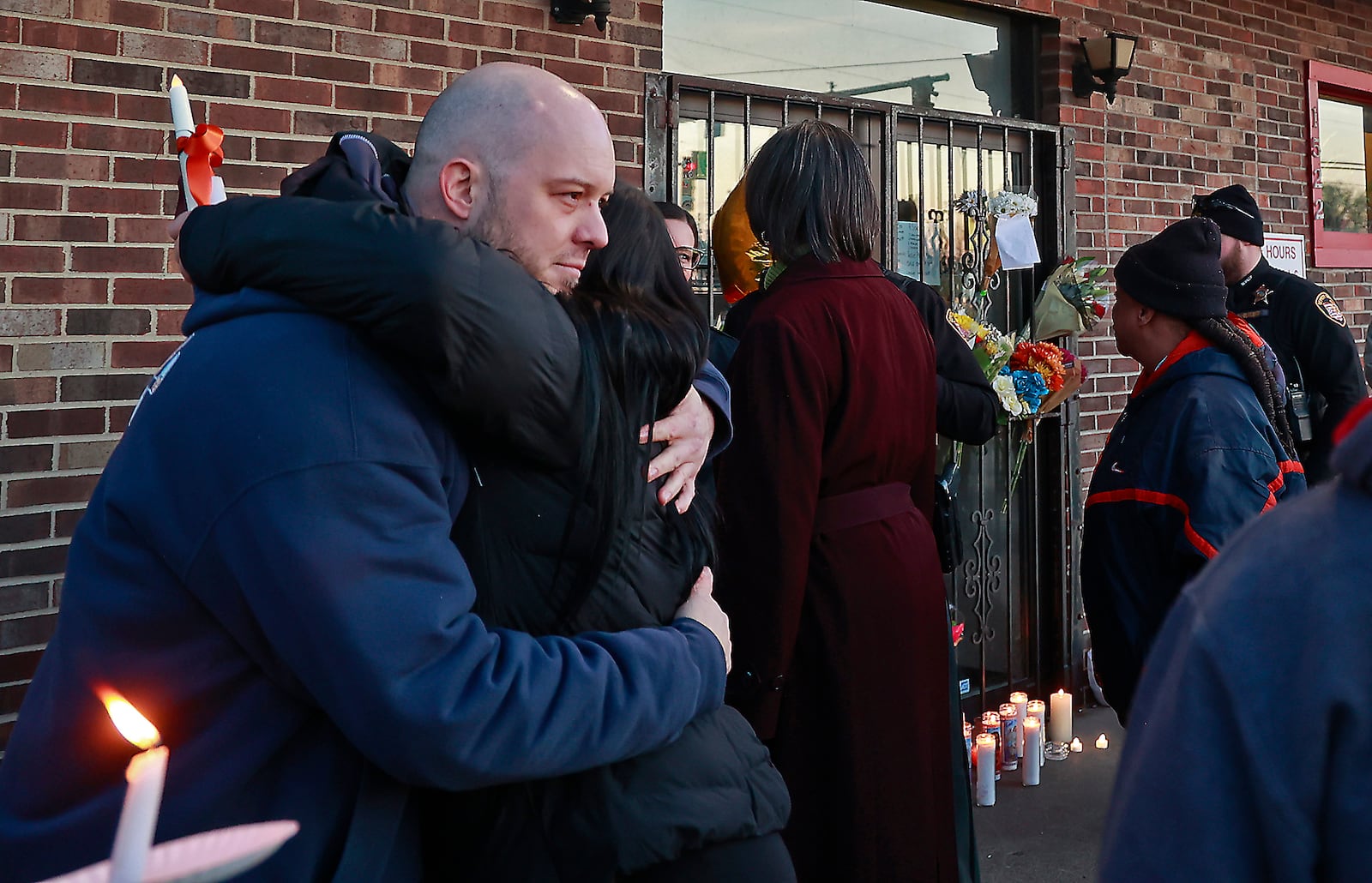 Shayne Gill, the son of Thomas Gill, who was shot and killed last Thursday in Springfield, gets a hug from a friend during a candle light vigil for his father in the parking lot of Gill's Quality Meats Monday, Jan. 9, 2023. BILL LACKEY/STAFF