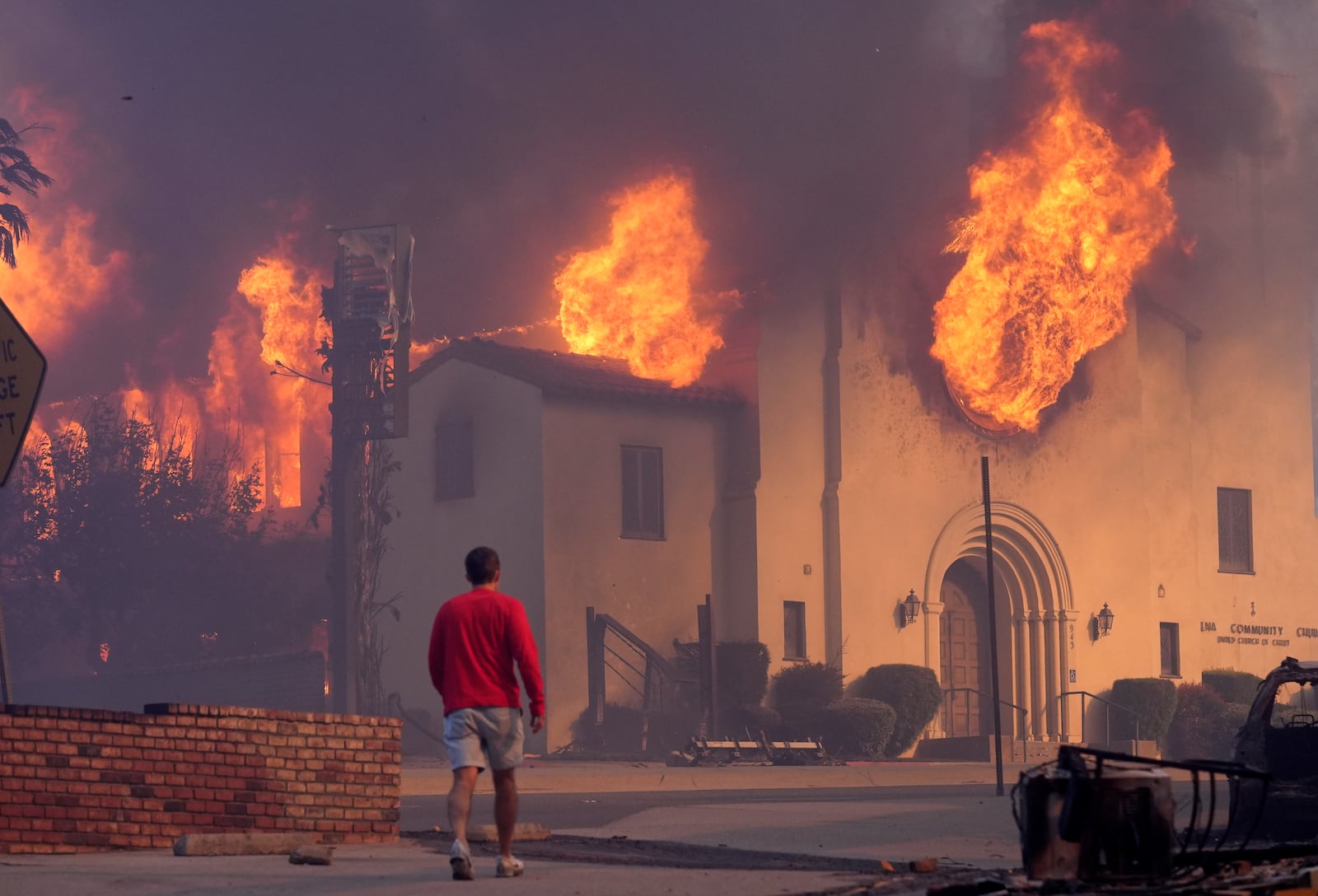 A man walks in front of the burning Altadena Community Church, Wednesday, Jan. 8, 2025, in in Pasadena, Calif. (AP Photo/Chris Pizzello)