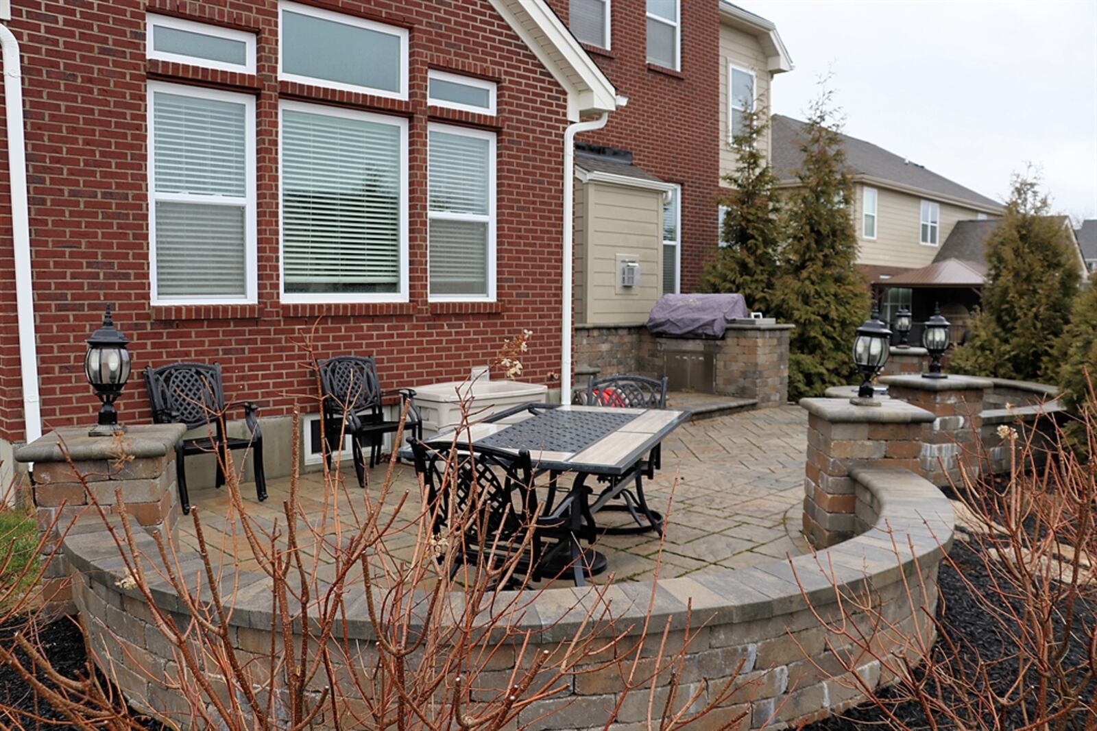 Lanterns accent column entry to the courtyard-like patio that has a built-in gas fire pit and a gas grill with added stone counterspace.