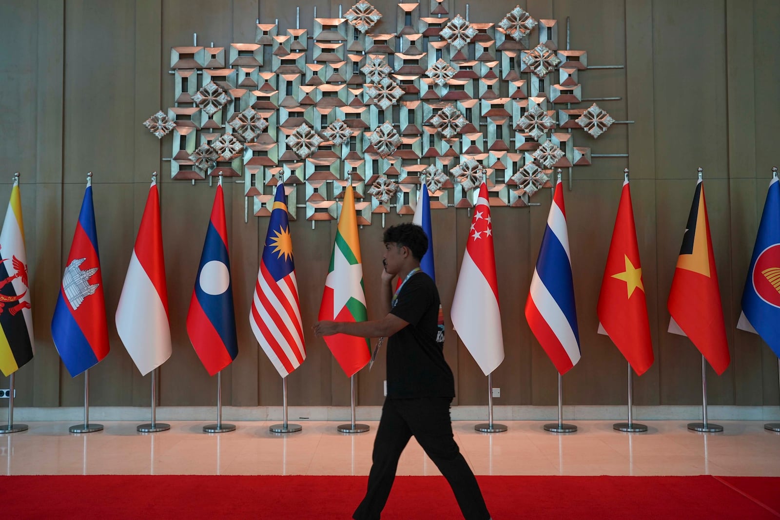 A man walk past the flags of the Association of Southeast Asian Nations' (ASEAN) members at a hotel where the ASEAN Foreign Ministers' Retreat (AMM) is taking place in Langkawi, Malaysia, on Saturday, January 18, 2025. (AP Photo/Azneal Ishak)