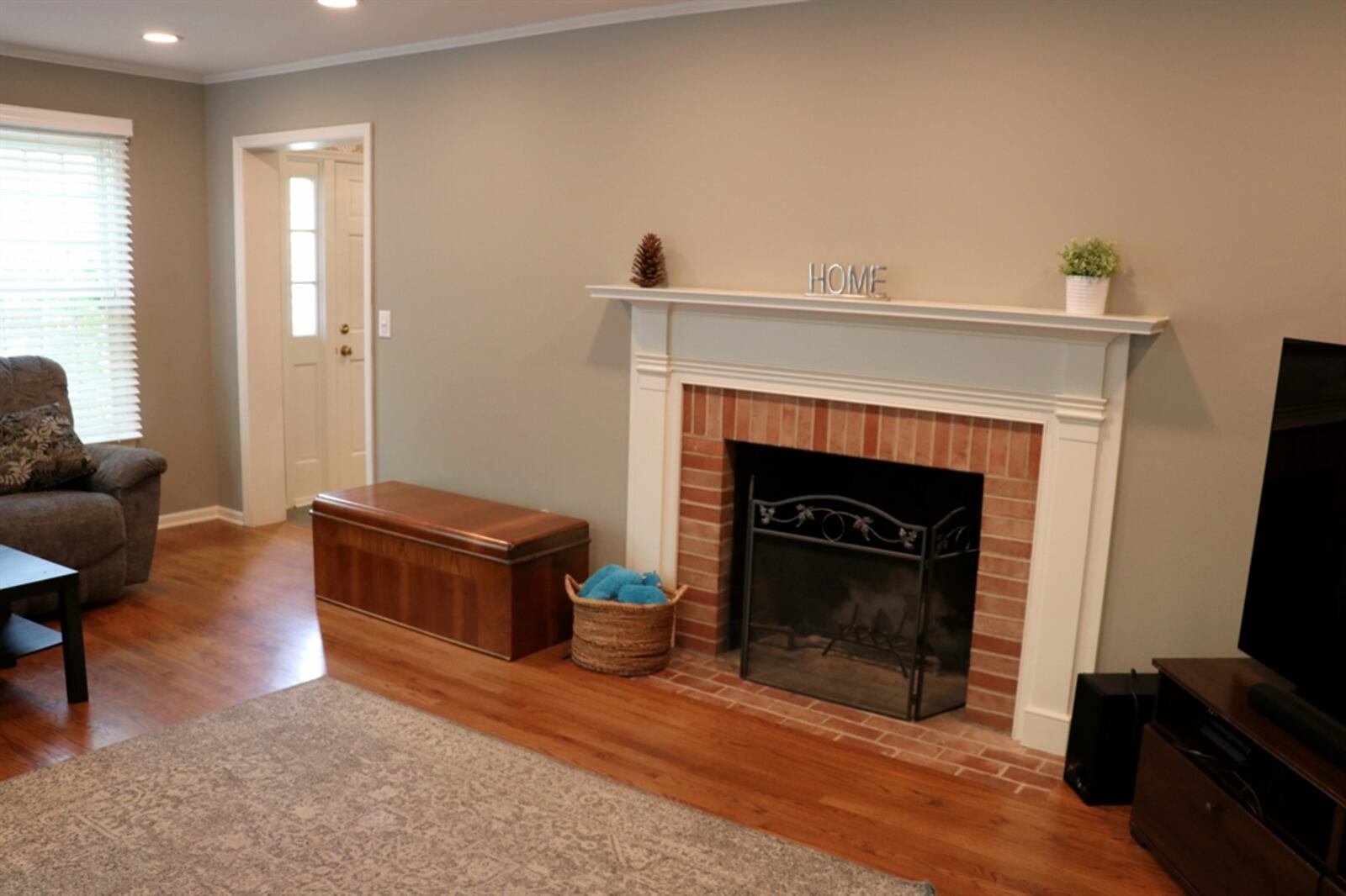 A wood-burning fireplace has a brick surround and wood mantel, and canister lighting fills the living room with added light. 