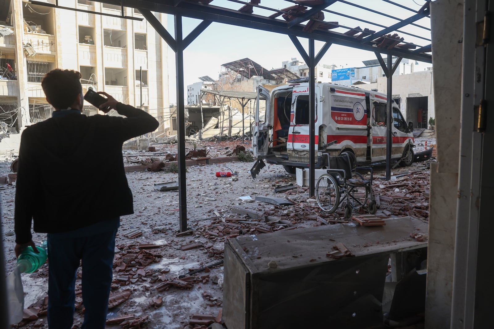 A man takes a pictures of a damaged ambulance after an airstrike outside a hospital complex in Idlib, Syria, Monday Dec.2, 2024.(AP Photo/Ghaith Alsayed)