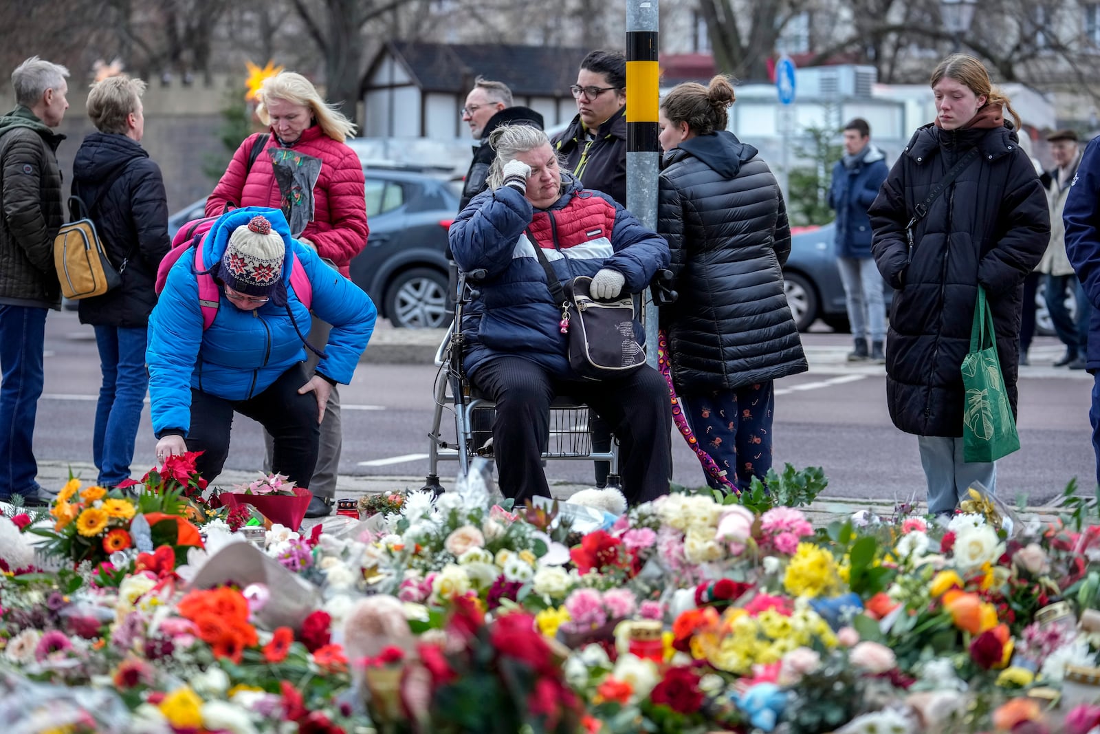 People lay flowers and candles in front of the Johannis church close to the Christmas market where a car drove into a crowd on Friday evening, in Magdeburg, Germany, Monday, Dec. 23, 2024. (AP Photo/Ebrahim Noroozi)