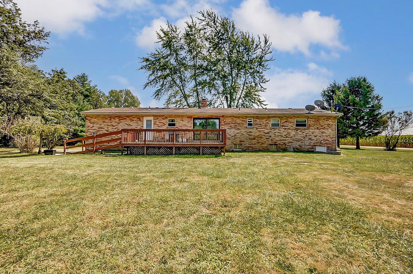 The rear of the home has a wood deck with railings and a ramp