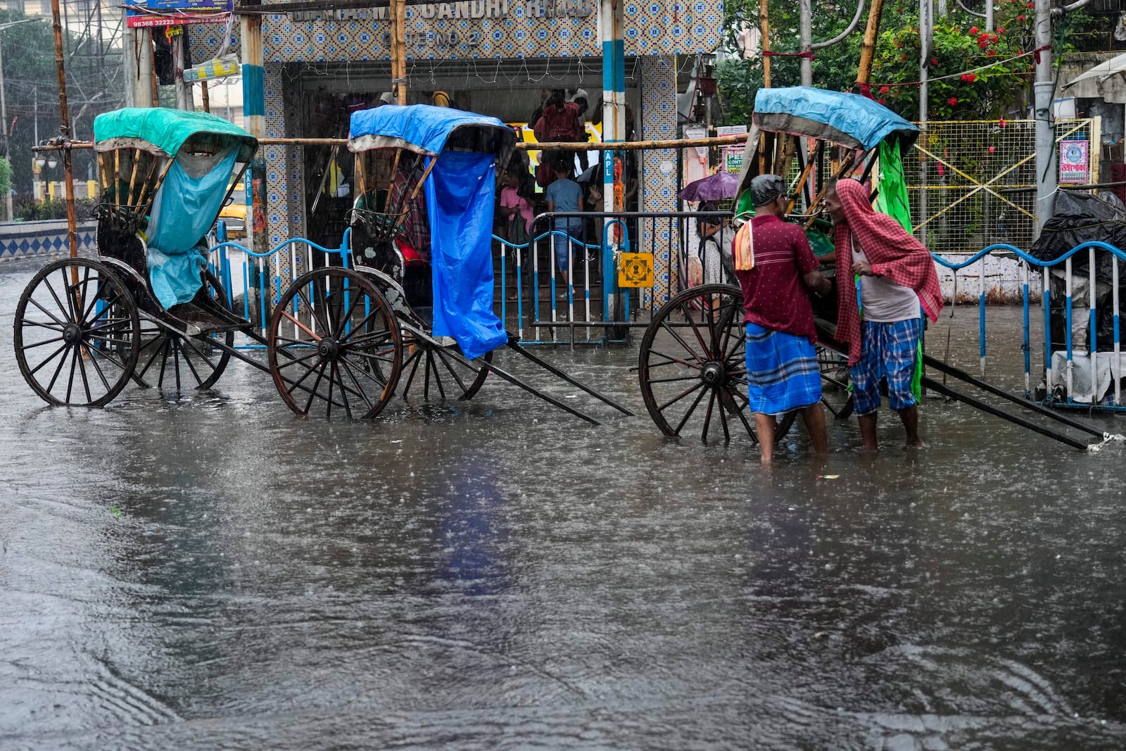 Hand-rickshaw pullers wait for customers on a waterlogged street during heavy rain following tropical storm Dana, in Kolkata, India, Friday, Oct. 25, 2024. (AP Photo/Bikas Das)