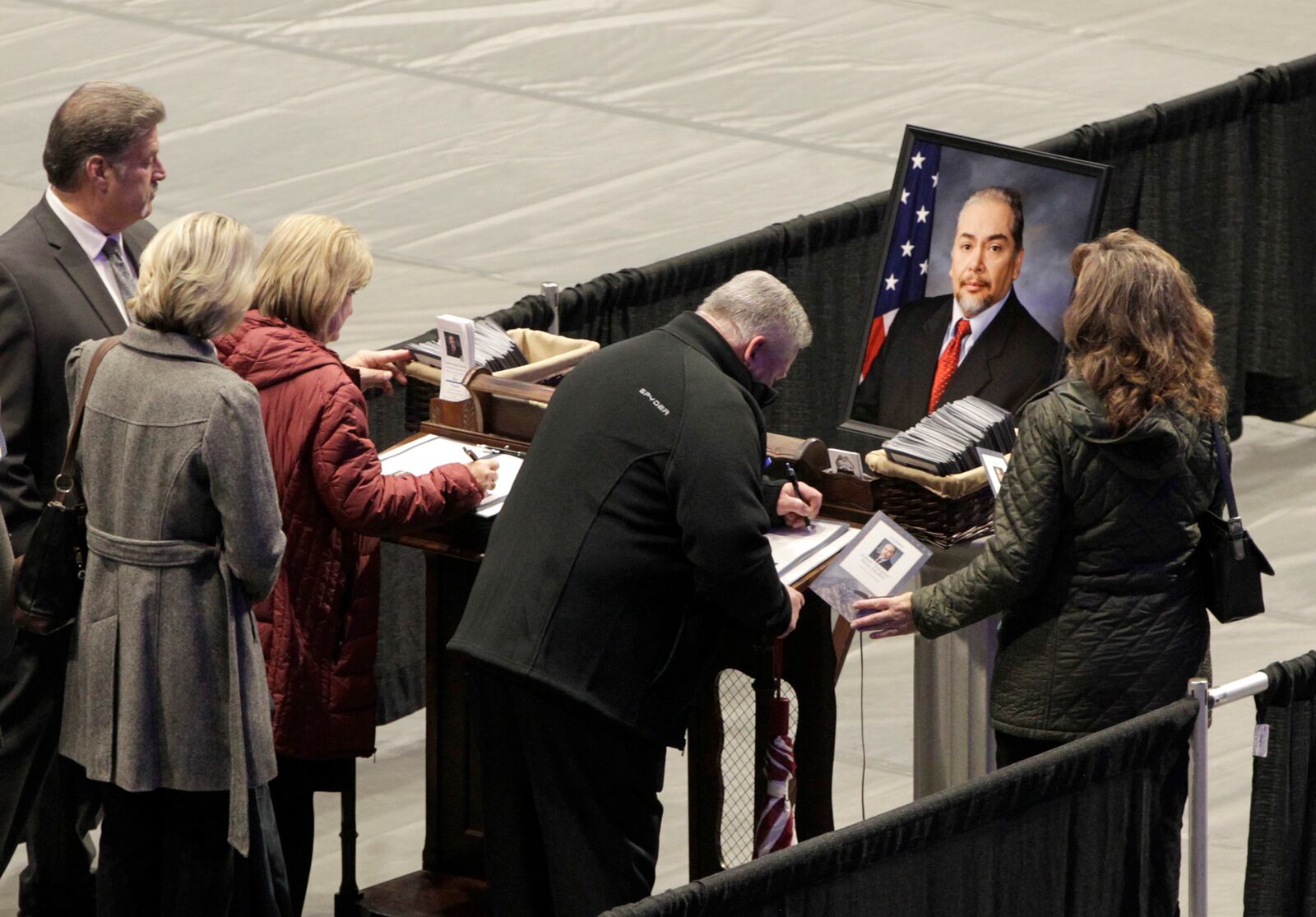 Visitors sign condolence books at the viewing for Dayton police Det. Jorge Del Rio Monday night at the University of Dayton Arena. Del Rio was shot Nov. 4 while serving a search warrant on a suspected drug house. Del Rio will be honored with a procession Tuesday, Nov. 12 that will carry him through Dayton and the surrounding communities to a private service at Tobias Funeral Home.  LISA POWELL / STAFF