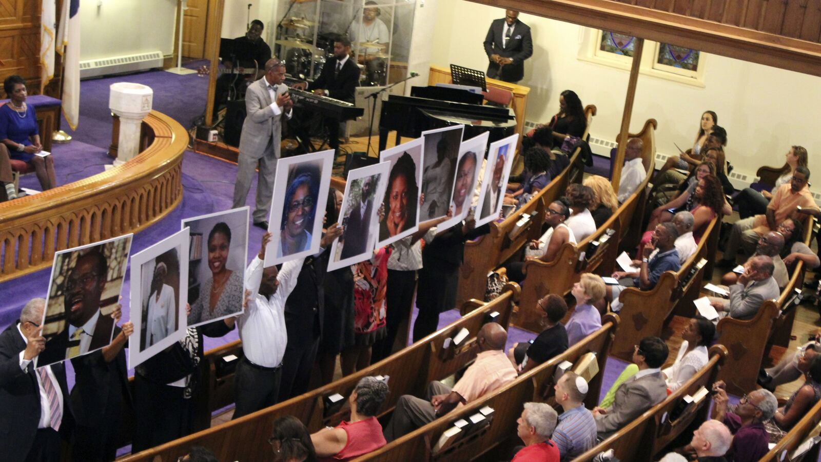 Photos of the victims of the Emanuel AME Church mass shooting in Charleston, S.C., are held up during a June 19, 2015, vigil at the Metropolitan African Methodist Episcopal Church in Washington. Emanuel's pastor and eight congregants were killed when Dylann Roof, a 21-year-old white supremacist, opened fire during a Bible study session.