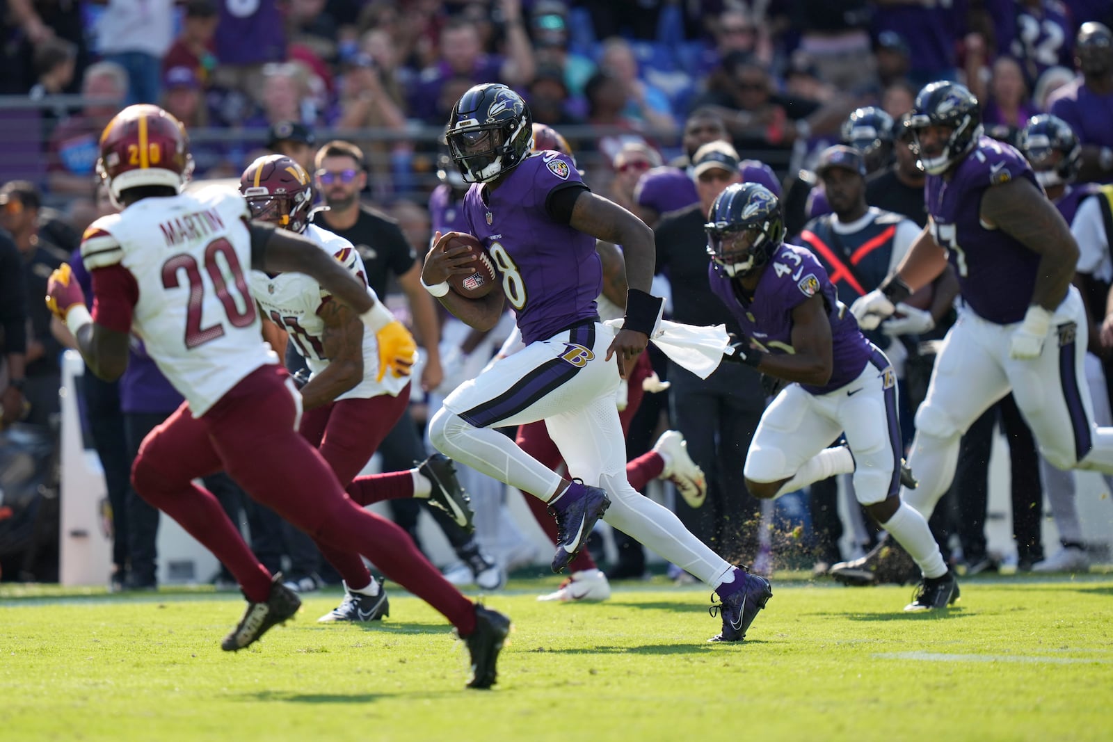 Baltimore Ravens quarterback Lamar Jackson (8) runs for a 33-yard gain as Washington Commanders safety Quan Martin (20) defends during the second half of an NFL football game Sunday, Oct. 13, 2024, in Baltimore. (AP Photo/Stephanie Scarbrough)