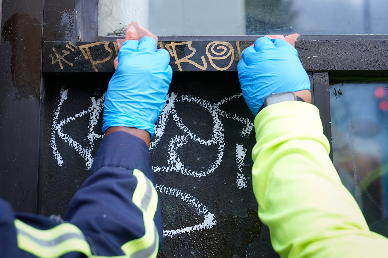 Queen Jones, left, and Dominique Medley, right, remove graffiti in a neighborhood of Washington, Tuesday, Aug. 20, 2024. (AP Photo/Susan Walsh)