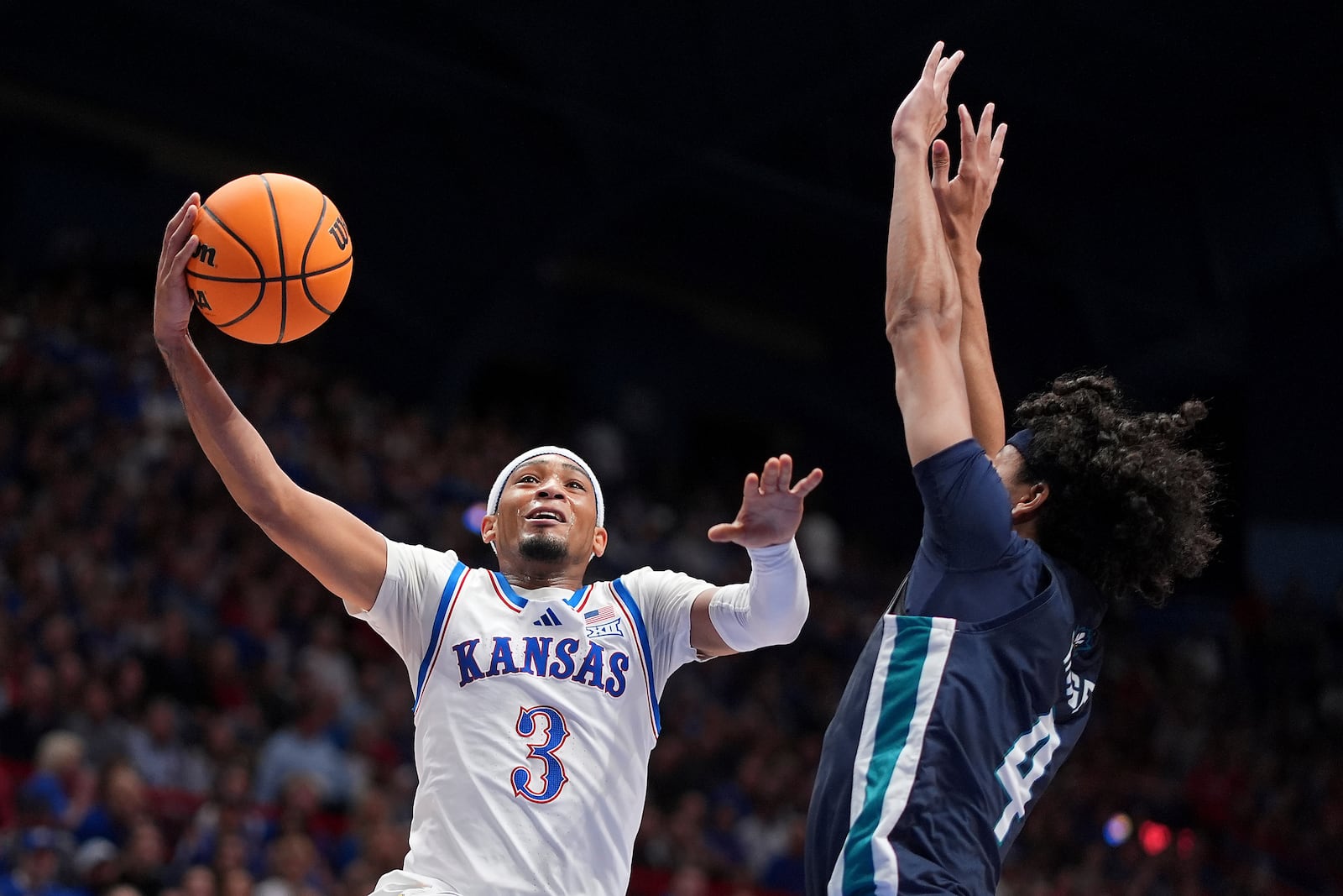 Kansas guard Dajuan Harris Jr. (3) shoots under pressure from UNC Wilmington guard Nolan Hodge (4) during the first half of an NCAA college basketball game Tuesday, Nov. 19, 2024, in Lawrence, Kan. (AP Photo/Charlie Riedel)