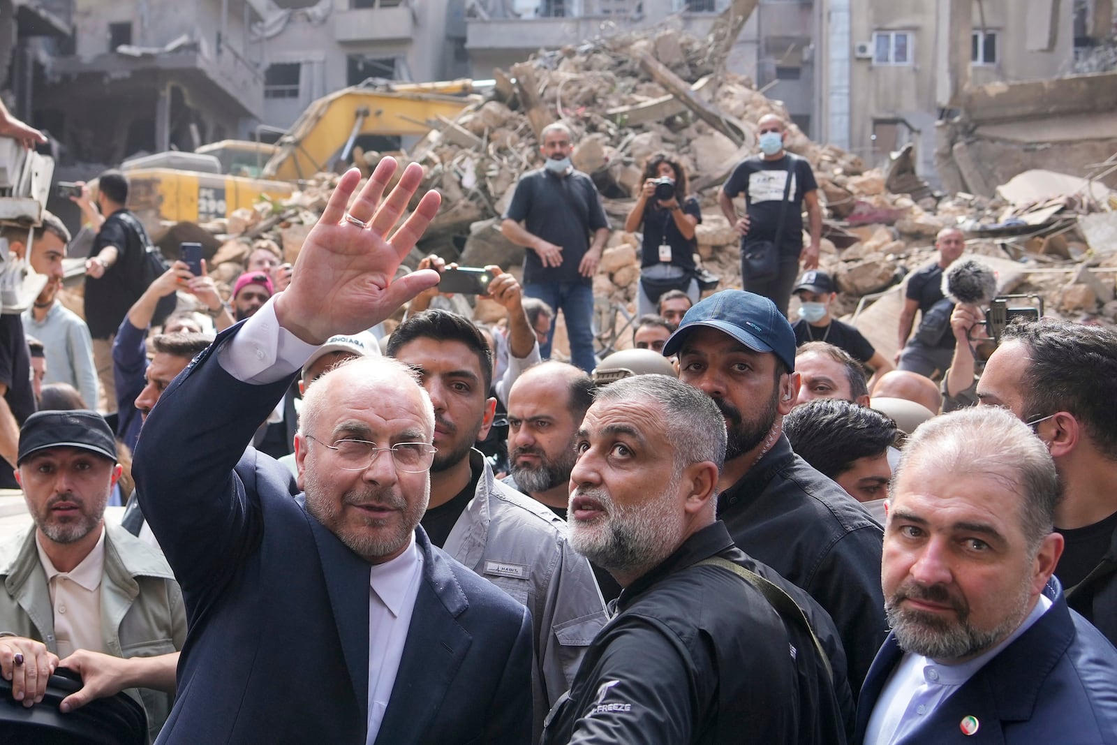 Iran's parliament speaker Mohammad Bagher Qalibaf, left, waves to residents as visit the site of Thursday's Israeli airstrike in Beirut, Lebanon, Saturday, Oct. 12, 2024. (AP Photo/Hassan Ammar)