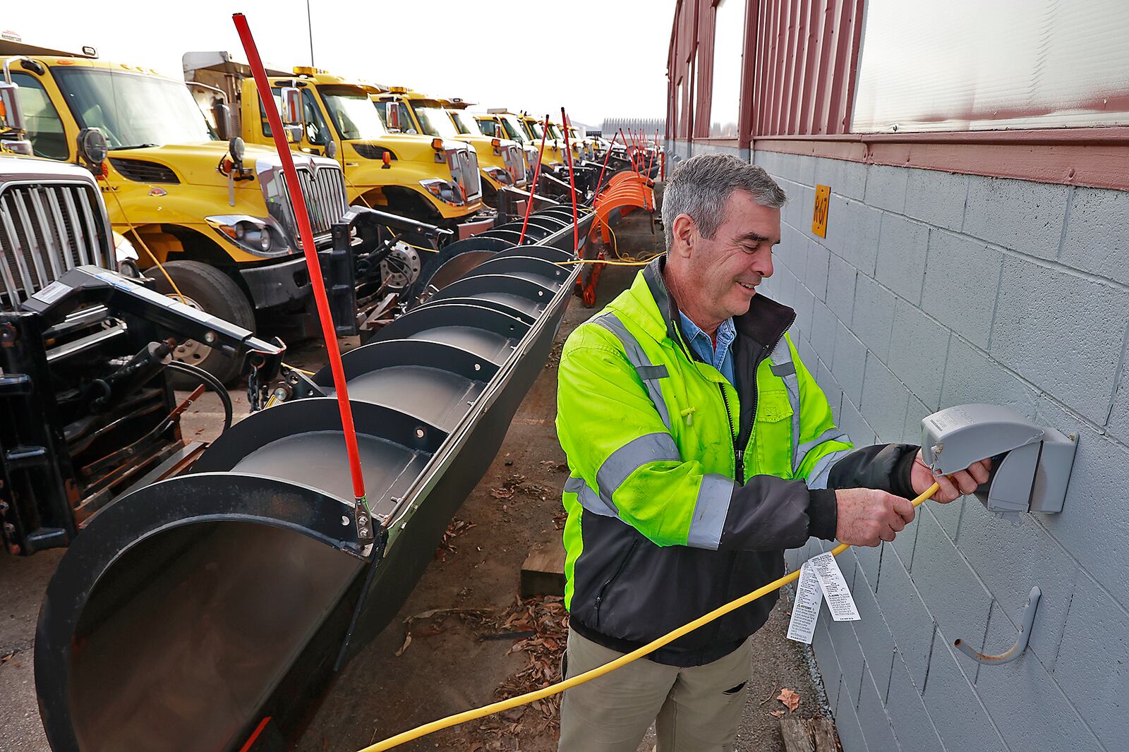 Mike Duffy, from the Clark County Engineers Office, plugs in one of the plow trucks at the county's garage Wednesday, Dec. 21, 2022. BILL LACKEY/STAFF