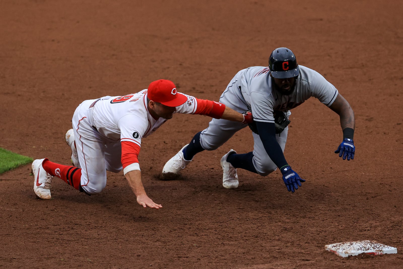 Cincinnati Reds' Joey Votto, left, dives and tags out Cleveland Indians' Franmil Reyes, right, for a triple play during the seventh inning of a baseball game in Cincinnati, Saturday, April 17, 2021. Indians' Josh Naylor lined out to Reds' Joey Votto to start the triple play. (AP Photo/Aaron Doster)