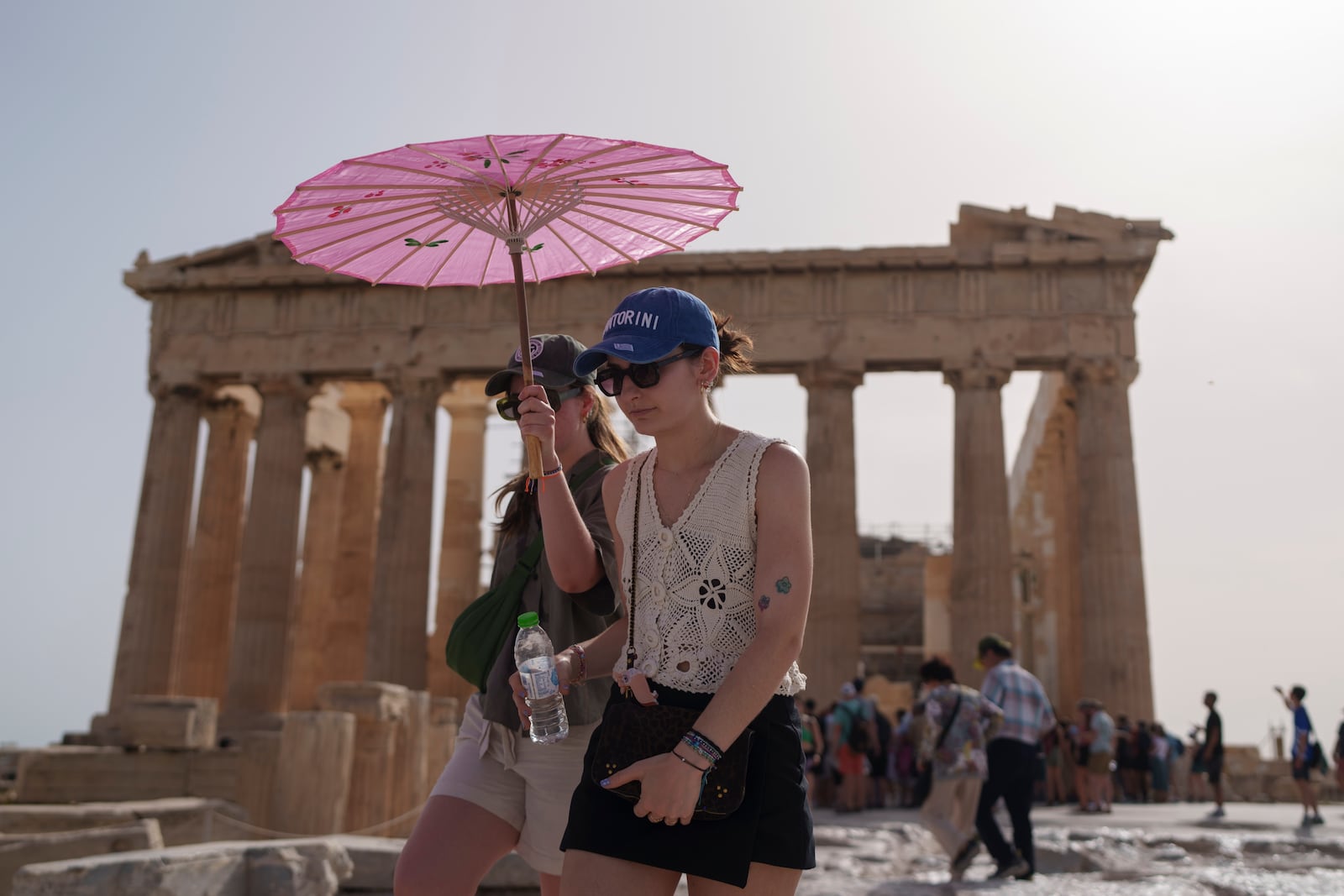 FILE - Tourists with an umbrella walk in front of the Parthenon at the ancient Acropolis in central Athens, June 12, 2024. June 2024 was the hottest June on record, according to Europe's Copernicus climate service on Monday, July 8. (AP Photo/Petros Giannakouris, File)