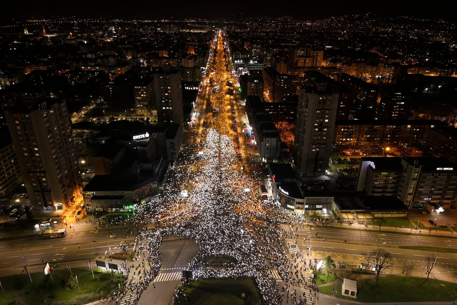 An aerial view of people hold up their mobile phone lights during a protest in front of a railway station where the collapse of a concrete canopy killed 15 people more than two months ago, in Novi Sad, Serbia, Friday, Jan. 31, 2025. (AP Photo/Armin Durgut)