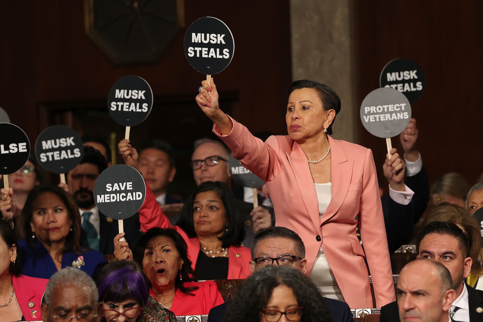 Rep. Nydia Velazquez, D-N.Y., holds a protest sign with fellow Democrats as President Donald Trump addresses a joint session of Congress at the Capitol in Washington, Tuesday, March 4, 2025. (Win McNamee/Pool Photo via AP)