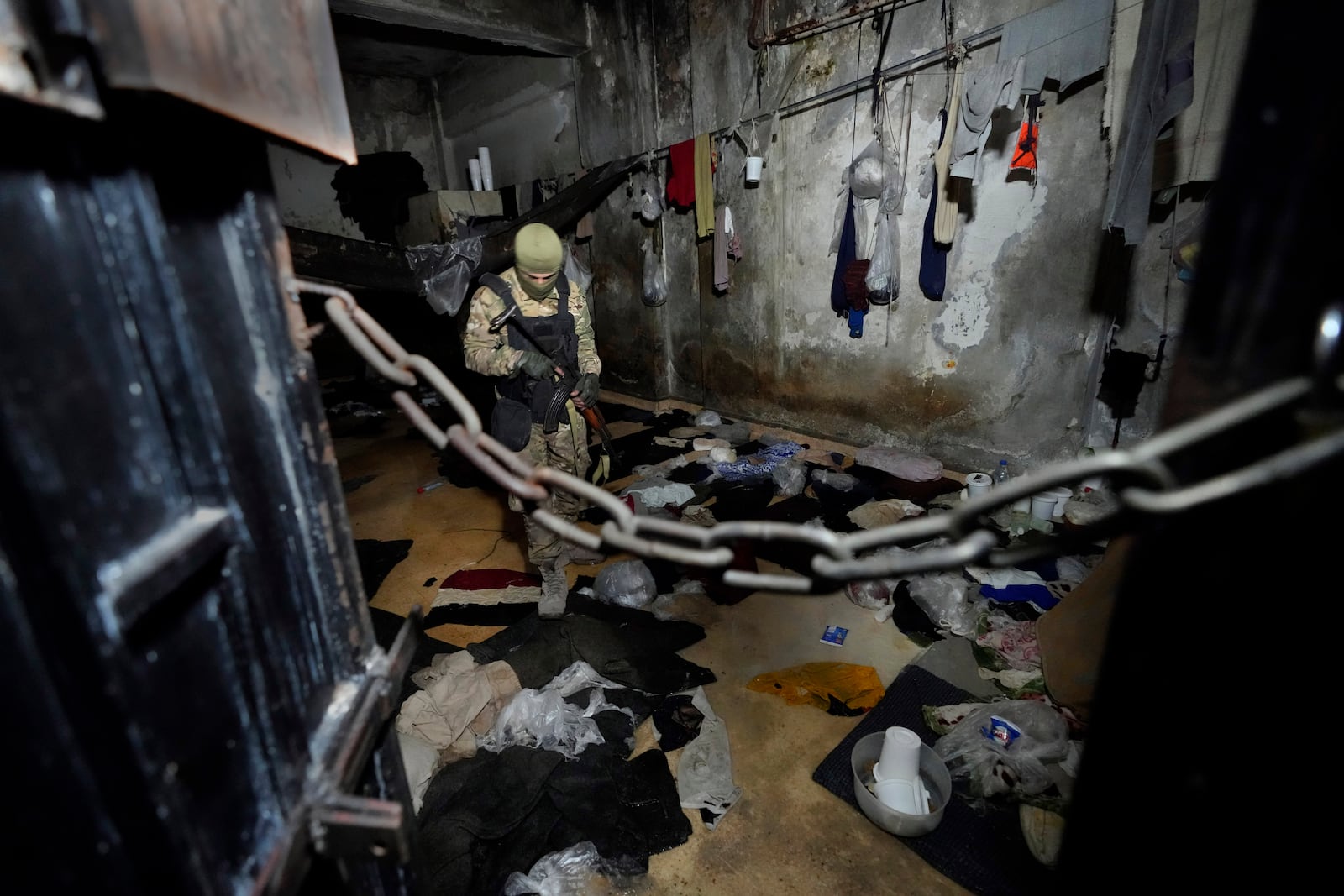 A Syrian fighter from rebel group, observes a prison room at the security detention center called Palestine Branch in Damascus, Syria, Saturday, Dec. 14, 2024. (AP Photo/Hussein Malla)