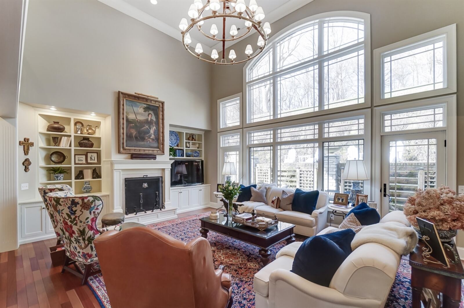 The two-story great room has built-in bookcases and cabinetry that surround a gas fireplace with wood mantel. 