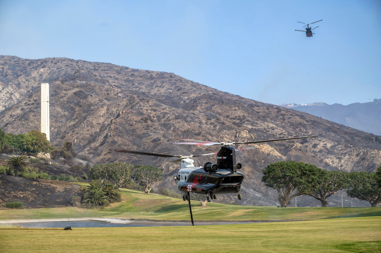 Firefighting helicopters fill their water tanks from a pond on the campus of Pepperdine University while battling the Franklin Fire on Tuesday, Dec. 10, 2024. (Hans Gutknecht/The Orange County Register via AP)