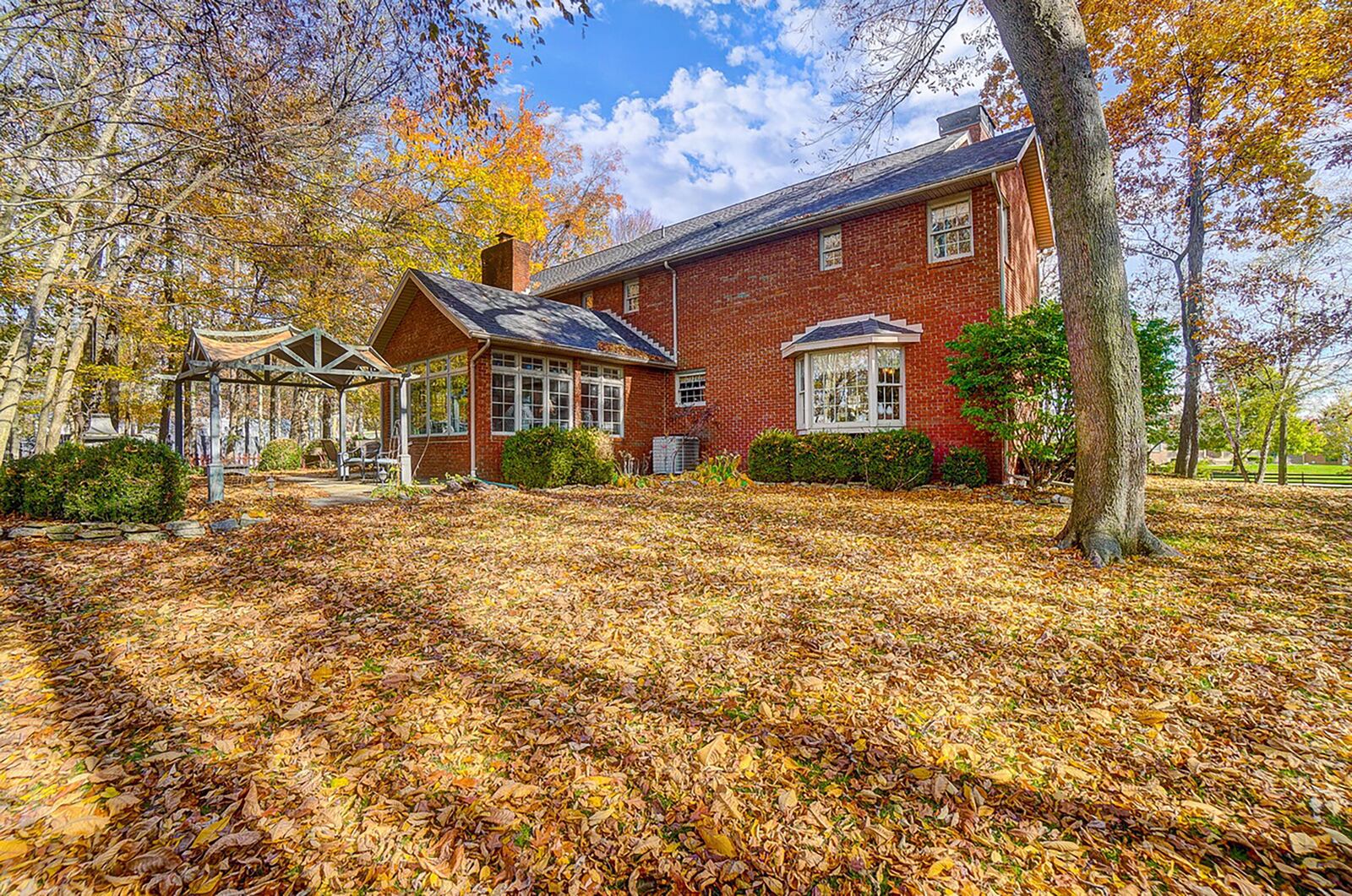 The rear of the home features a concrete patio with wood gazebo and a fully enclosed sun room overlooking the back yard.