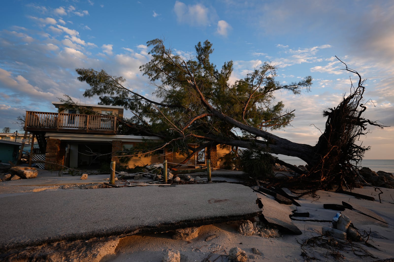 A tree lies toppled on a home alongside a broken road following Hurricane Milton, on Manasota Key, Fla., Saturday, Oct. 12, 2024. (AP Photo/Rebecca Blackwell)