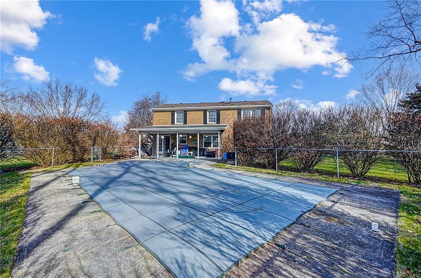 The rear of the home has an inground pool with a diving board, covered concrete patio and two fences, including a pool fence.