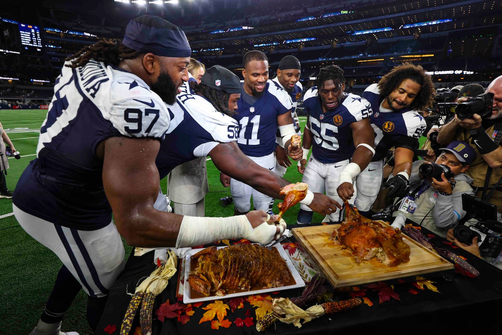 Dallas Cowboy players grab some turkey following an NFL football game against the New York Giants in Arlington, Texas, Thursday, Nov. 28, 2024. (AP Photo/Richard Roriguez)