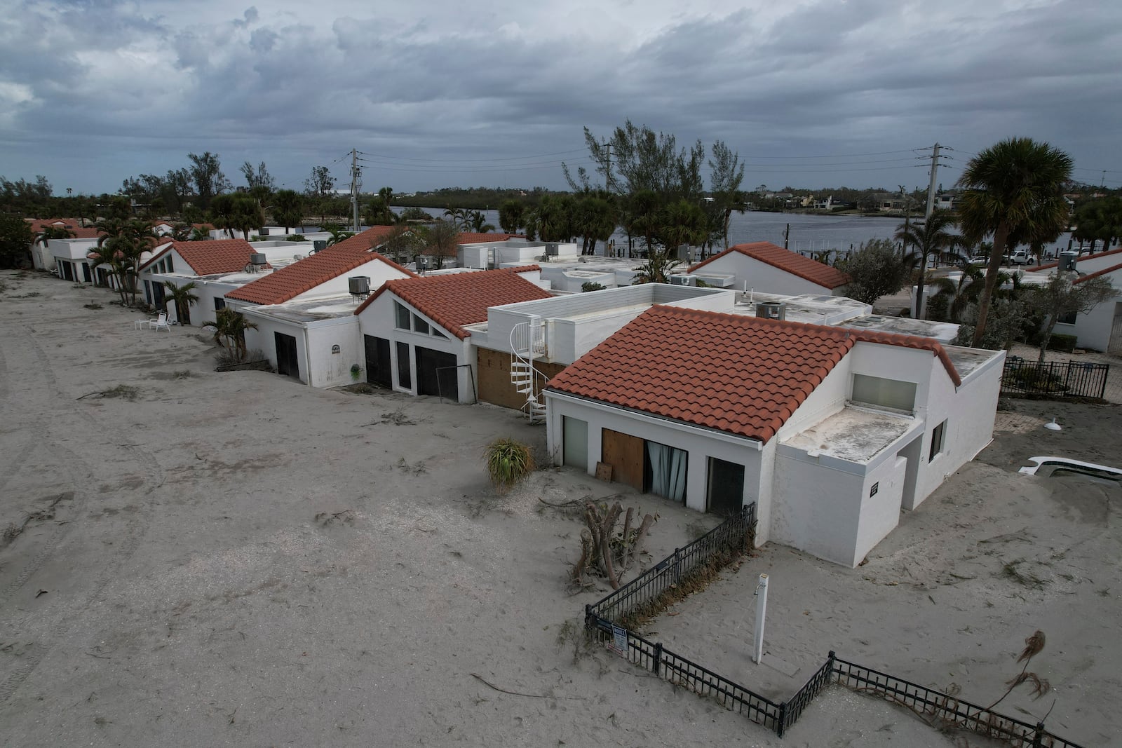 Sand swept by Hurricane Milton reaches half-way up the sliding doors of a beachfront villa, next to a pool deck where the 8 1/2 foot deep pool had disappeared under sand, at Jetty Villas on the island of Venice, Fla., Friday, Oct. 11, 2024. (AP Photo/Rebecca Blackwell)