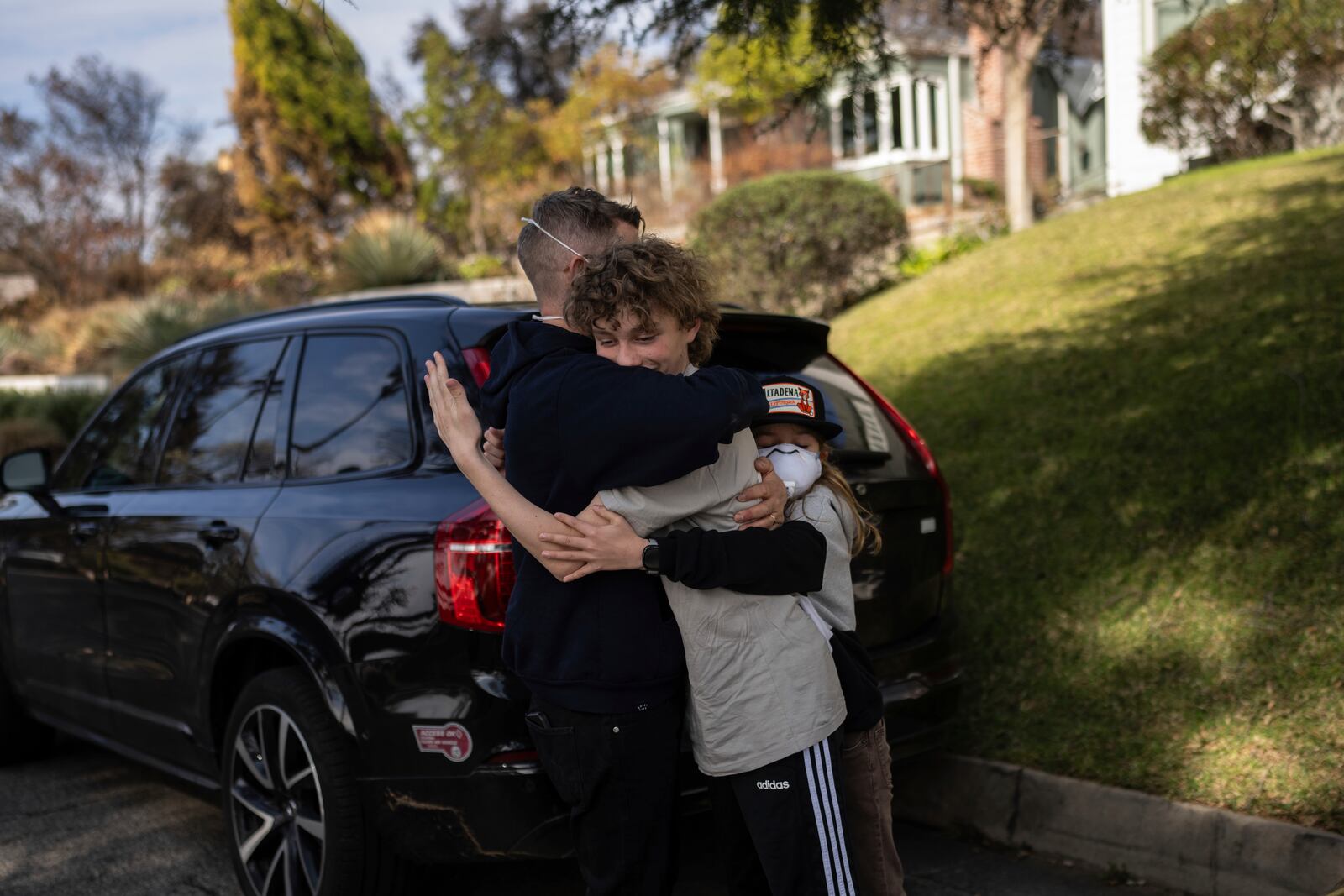 Eaton Fire evacuees Ceiba Phillips, right, and his father, Craig, hug Ceiba's best friend, Julian Trobiani, whose home was devastated by the fire, on Ceiba's first visit to his home since the fire in Altadena, Calif., Saturday, Feb. 8, 2025. (AP Photo/Jae C. Hong)