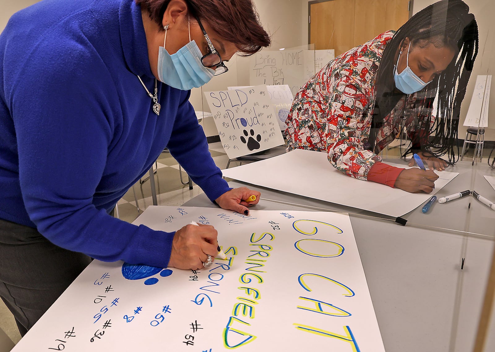 Anna Plataniotis, left, and Sherita Bloxom joined several other employees at the Rocking Horse Center in making signs to show their support for the Springfield Wildcats in the state football playoffs. The employees are planning to stand along South Limestone and cheer as the Wildcats leave for their game. BILL LACKEY/STAFF