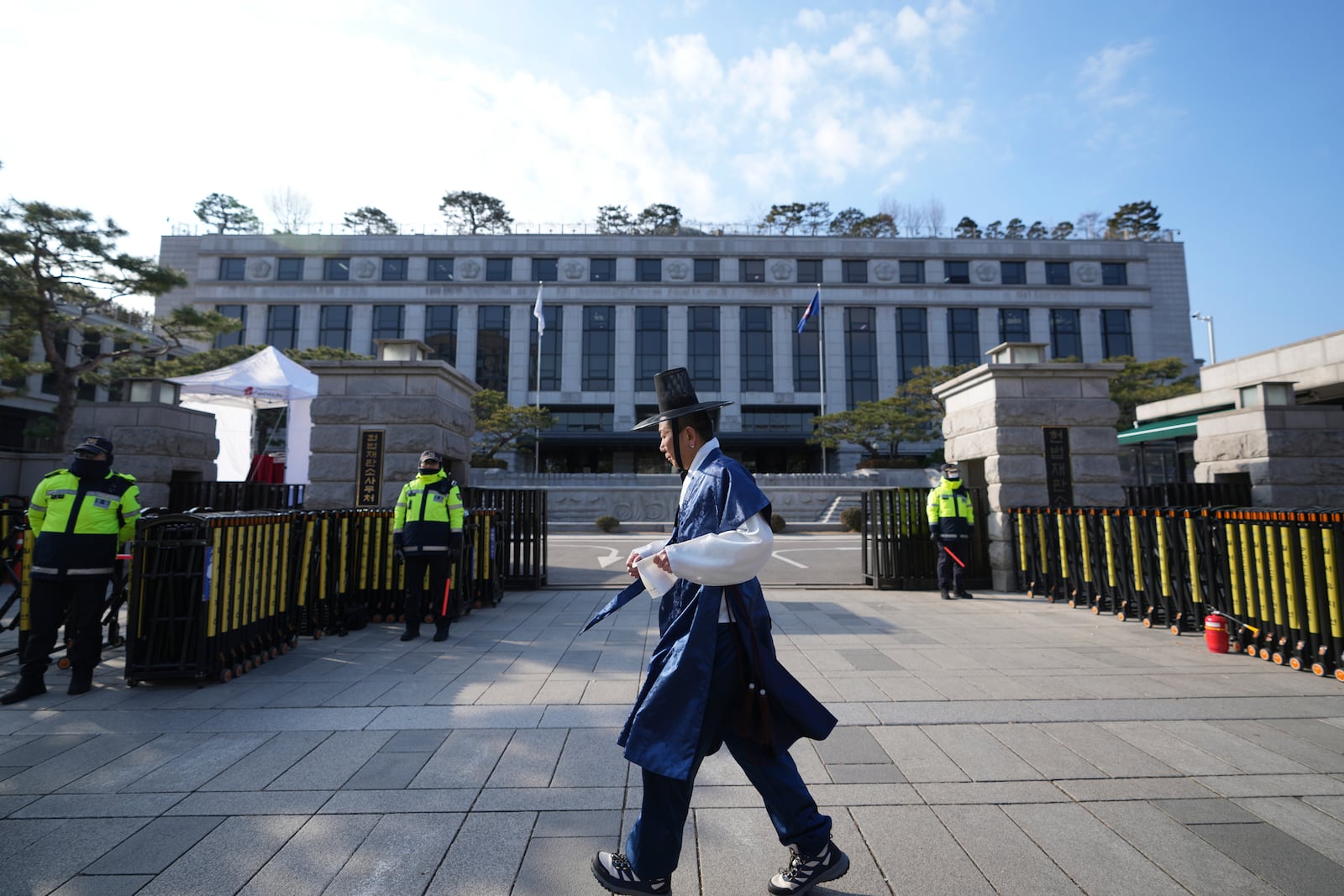 A visitor wearing South Korean traditional costume "Hanbok" walks past in front of the Constitutional Court in Seoul, South Korea, Tuesday, Dec. 17, 2024. (AP Photo/Lee Jin-man)