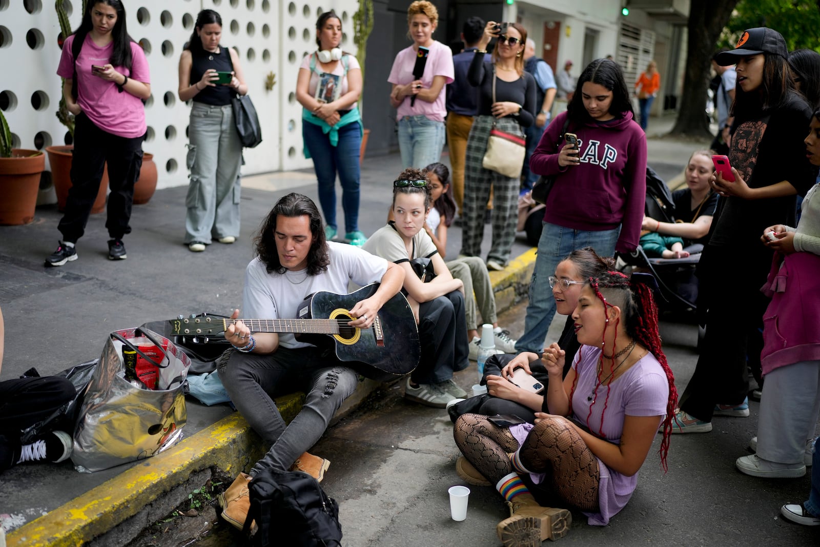 Fans sing in honor of former One Direction singer Liam Payne outside the hotel where he was found dead after falling from a balcony in Buenos Aires, Argentina, Thursday, Oct. 17, 2024. (AP Photo/Natacha Pisarenko)