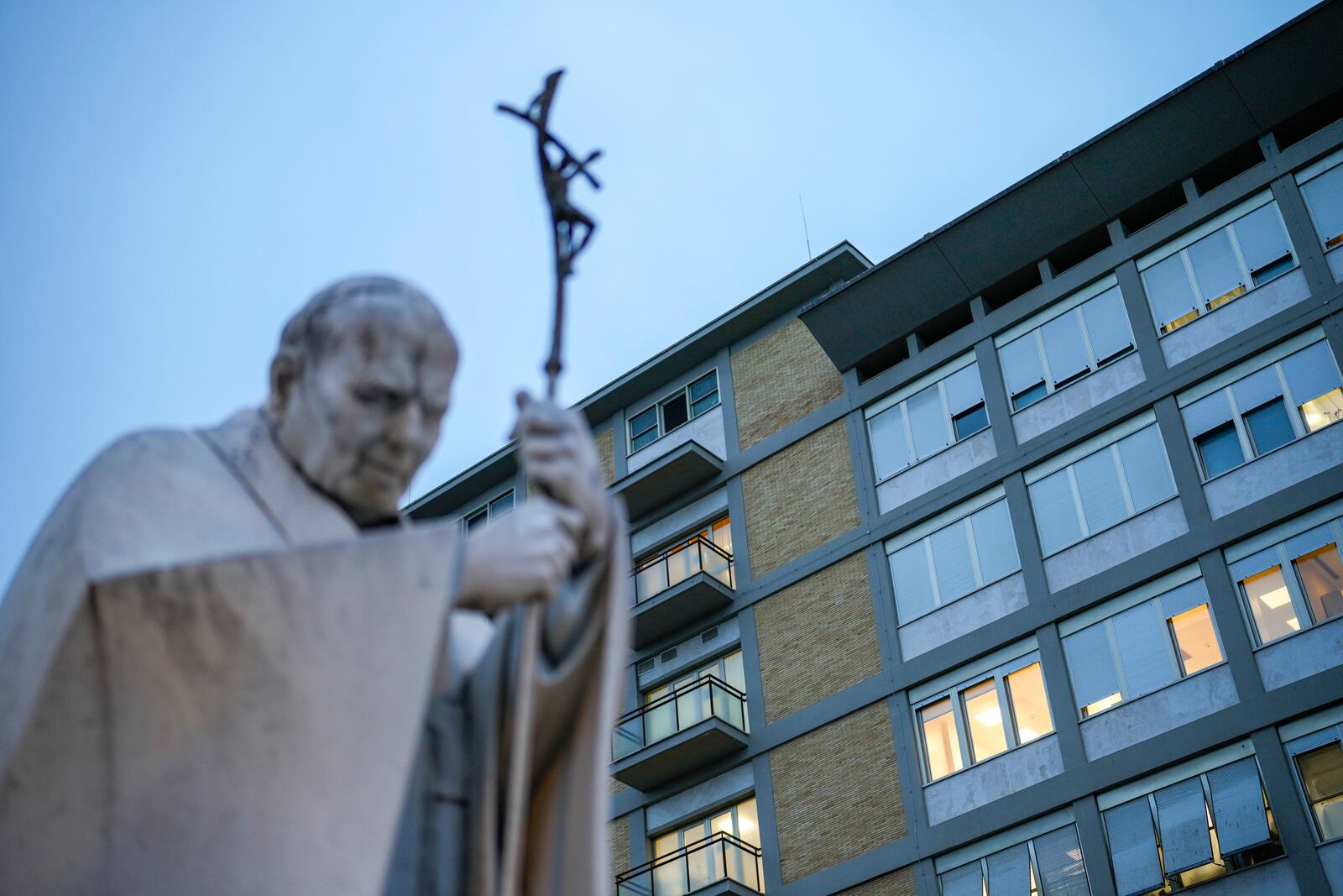 A marble statue of late Pope John Paul II is backdropped by the Agostino Gemelli Polyclinic in Rome, Saturday, Feb. 15, 2025, where Pope Francis was hospitalized Friday after a weeklong bout of bronchitis worsened and is receiving drug therapy for a respiratory tract infection. (AP Photo/Gregorio Borgia)