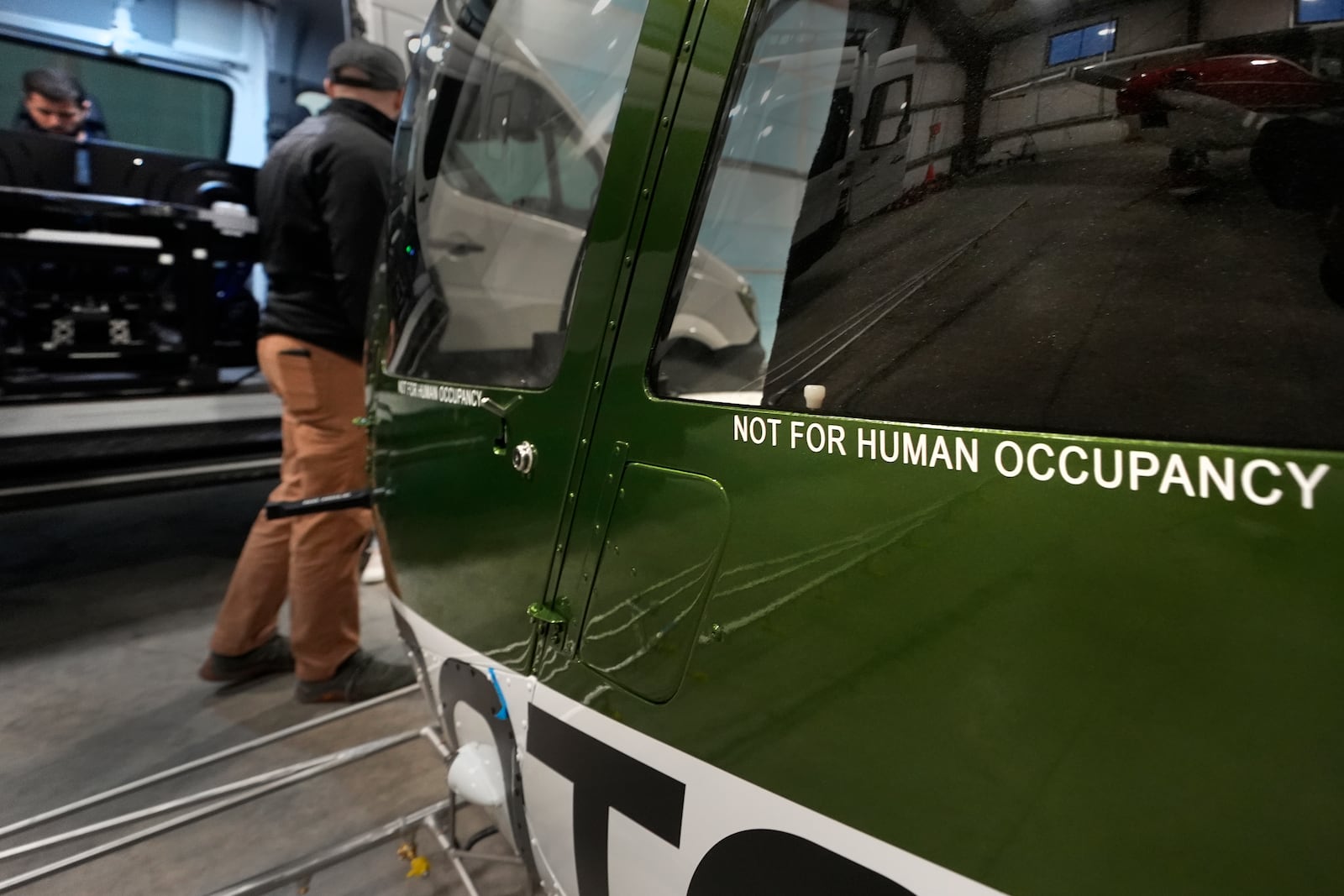 Test pilot Joao Magioni, seated left, talks with production manager Brett Worden while preparing a flight of a Rotor Technologies unmanned semi-autonomous helicopter in a hanger at Intervale Airport, Monday, Nov. 11, 2024, in Henniker, N.H. (AP Photo/Charles Krupa)